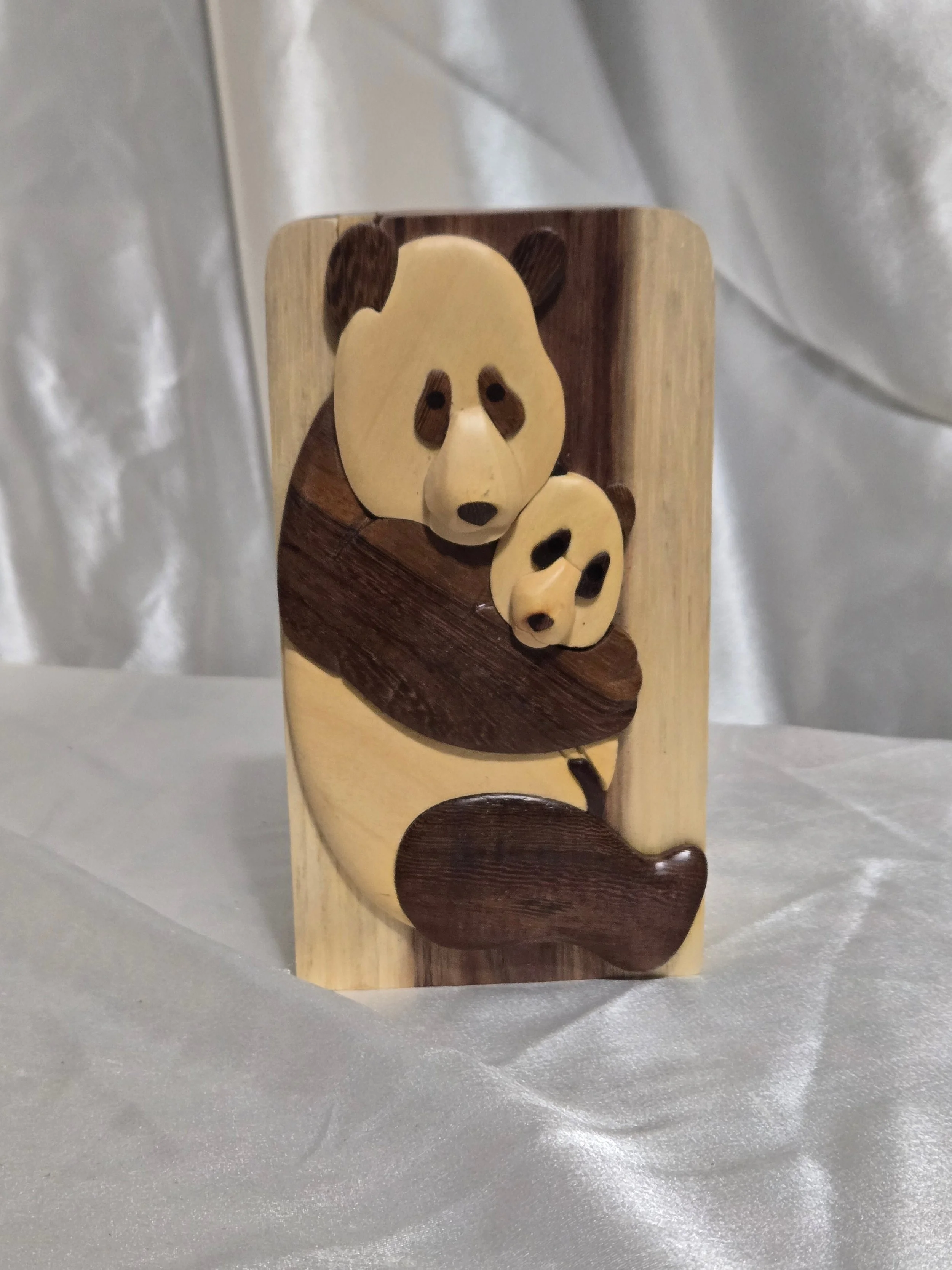 Handcrafted wooden panda puzzle box by Carver Dan on silver backdrop