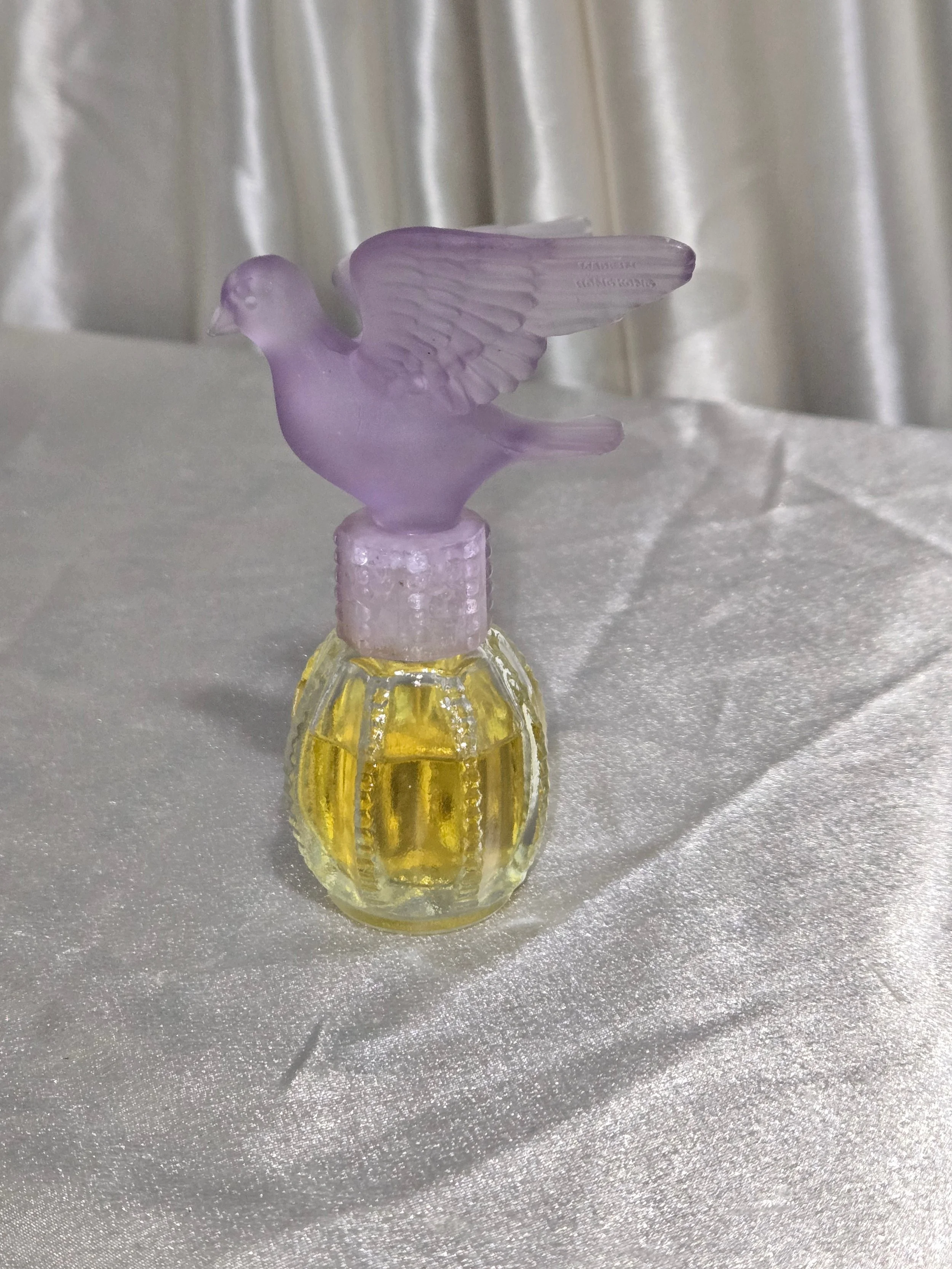 Side angle of Avon Delager Royal purple dove perfume bottle showing wing details and glass texture