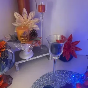 Decorative table with colorful flowers, glass candle holder, and drinks, illuminated by blue and purple lighting.
