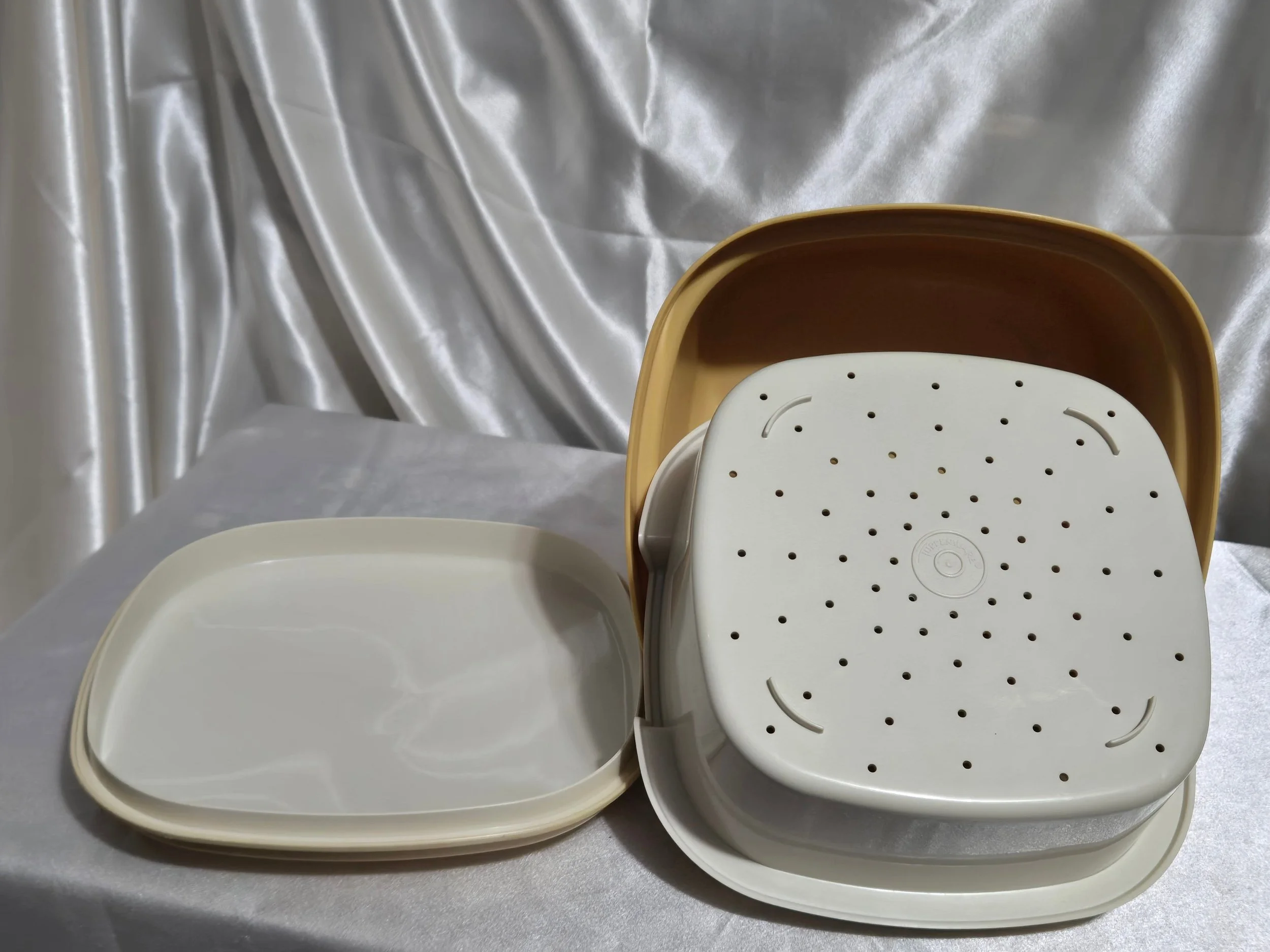 Vintage Tupperware microwave steamer in mustard yellow and ivory with lid upside down , vented insert upside down, and base shown together.