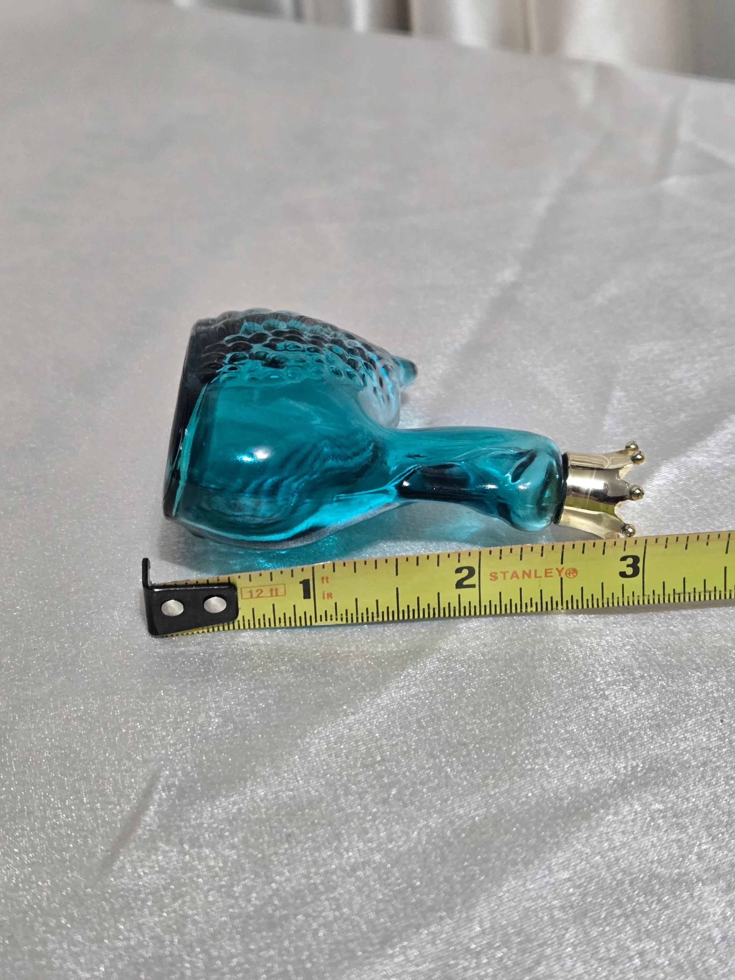 Vintage Avon swan perfume bottle in teal glass displayed with measuring tape for scale.