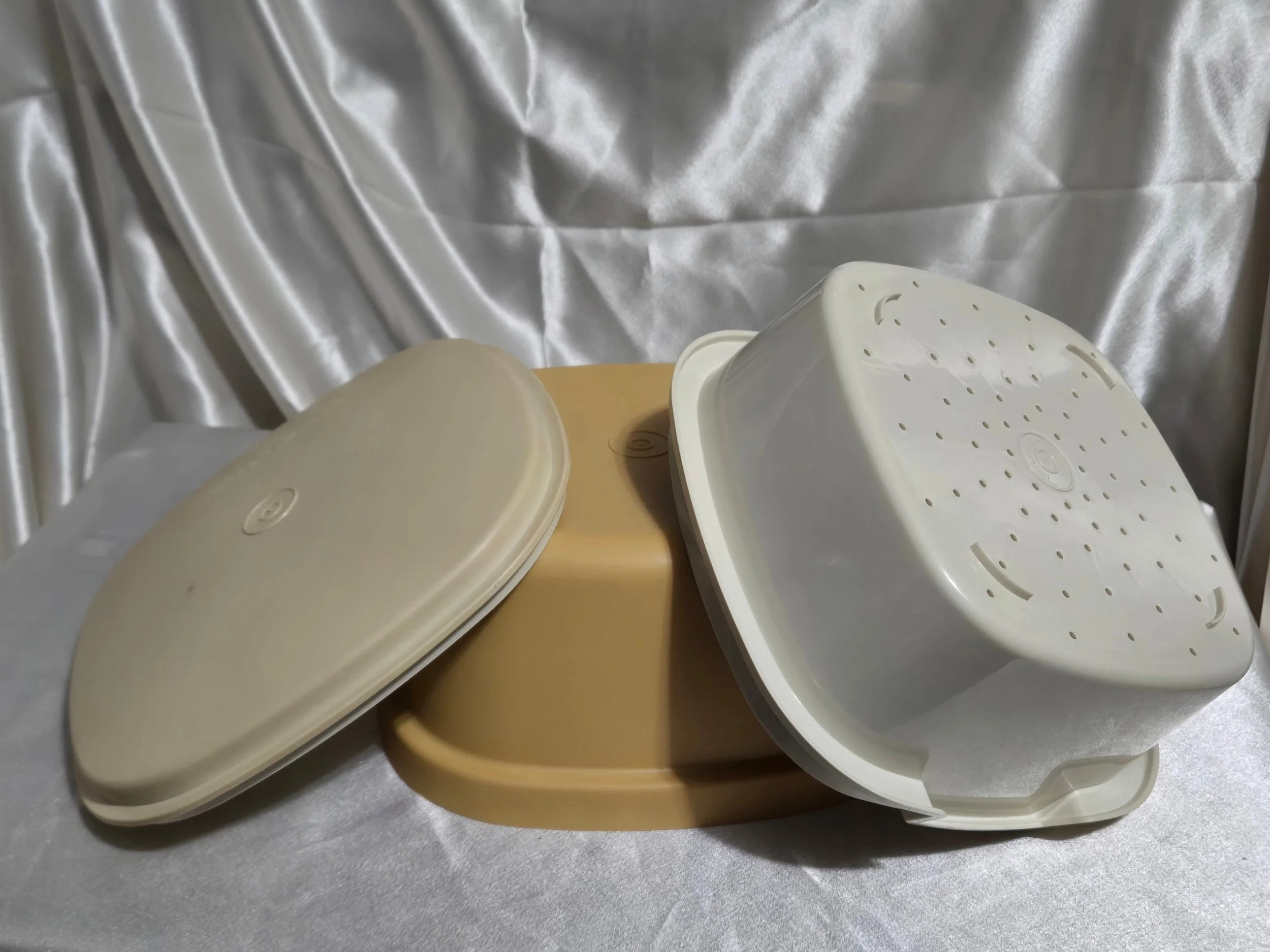Vintage Tupperware microwave steamer in mustard yellow and ivory with lid, vented insert, and base all inverted and shown together.