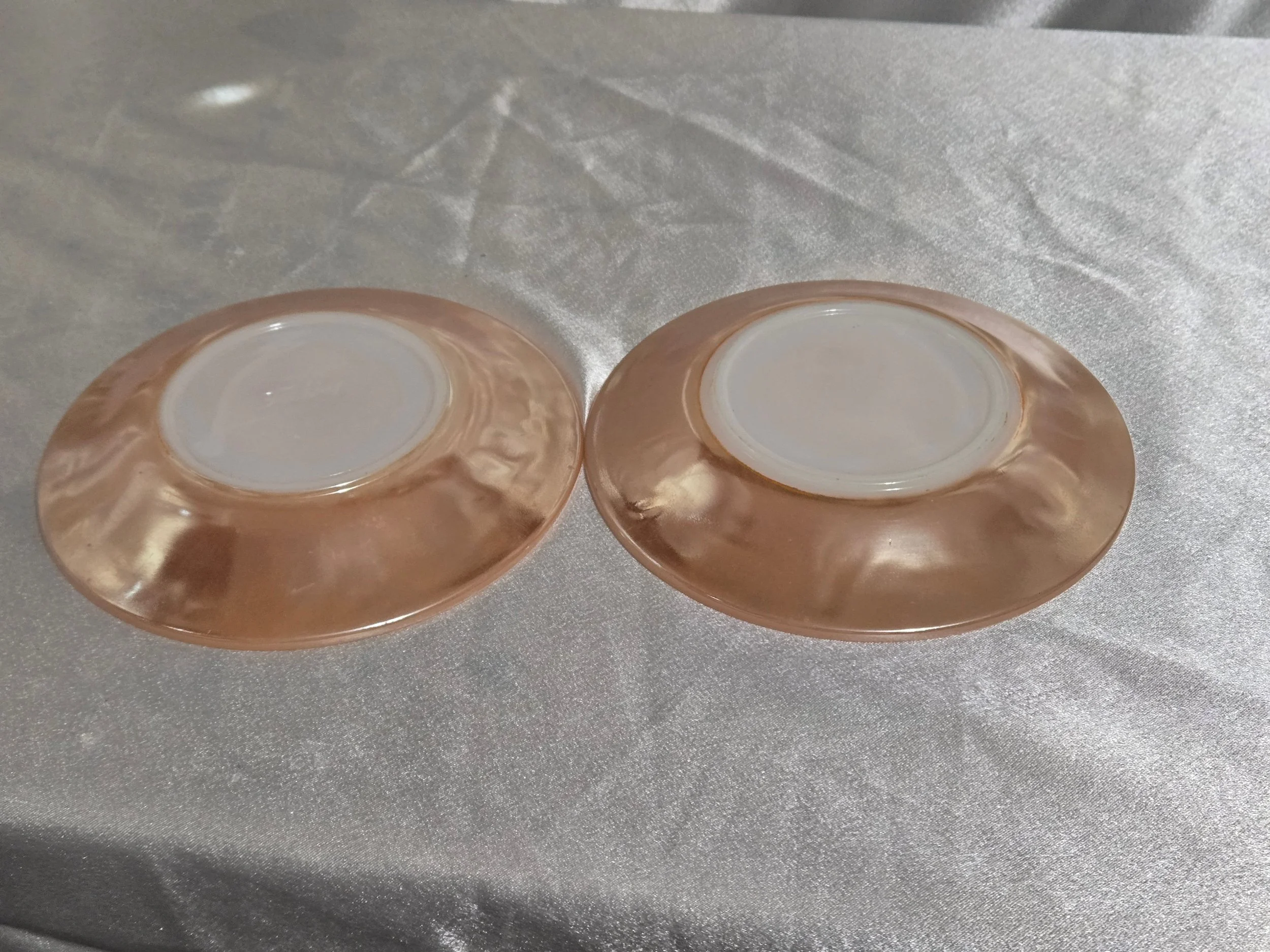 Set of Fire-King Peach Lustre saucers with iridescent sheen and vintage mid-century glow against white background.