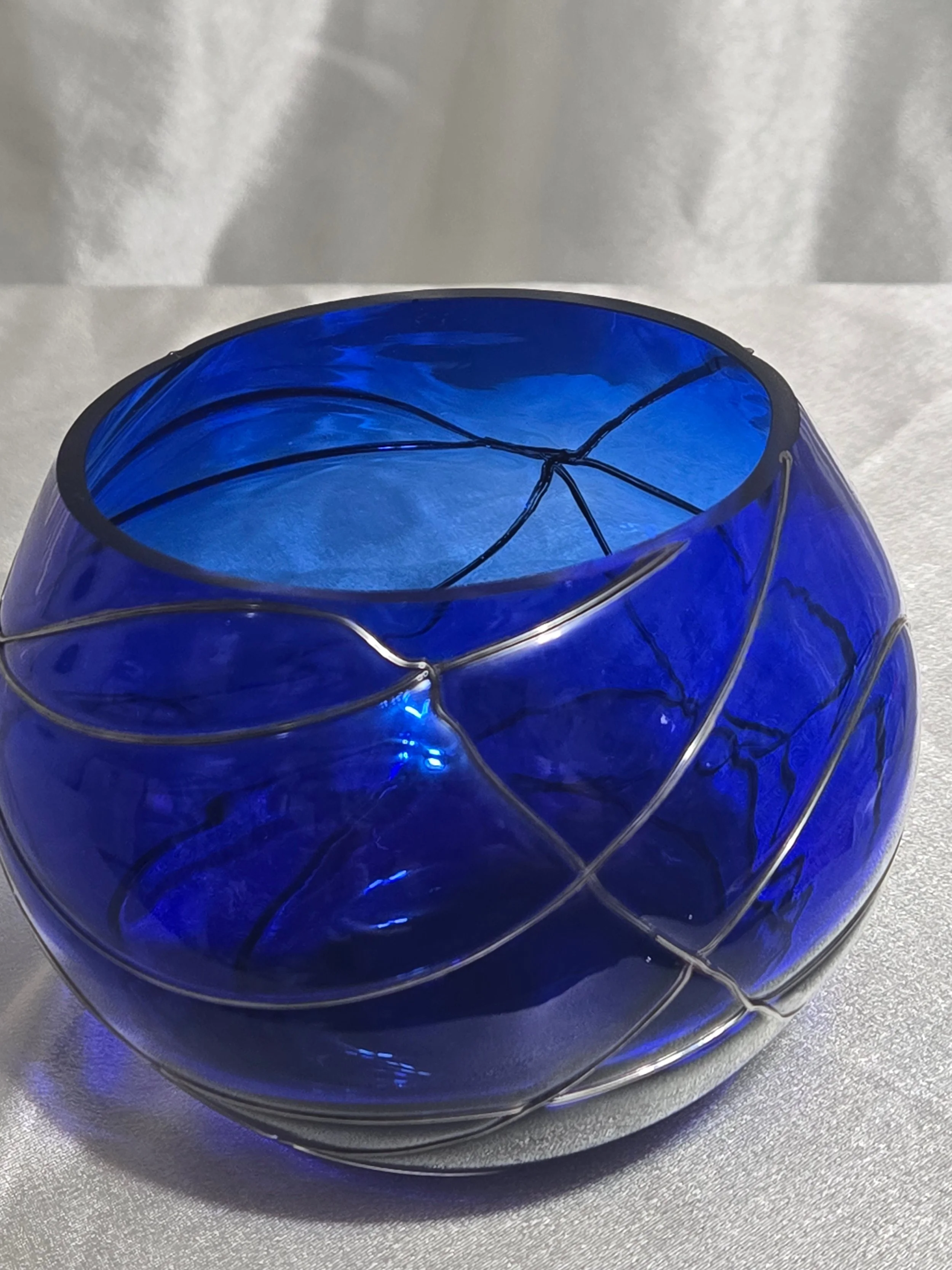 Cobalt blue hand-blown glass vase with silver swirl detailing, rounded art glass bowl, Murano-style decorative piece.