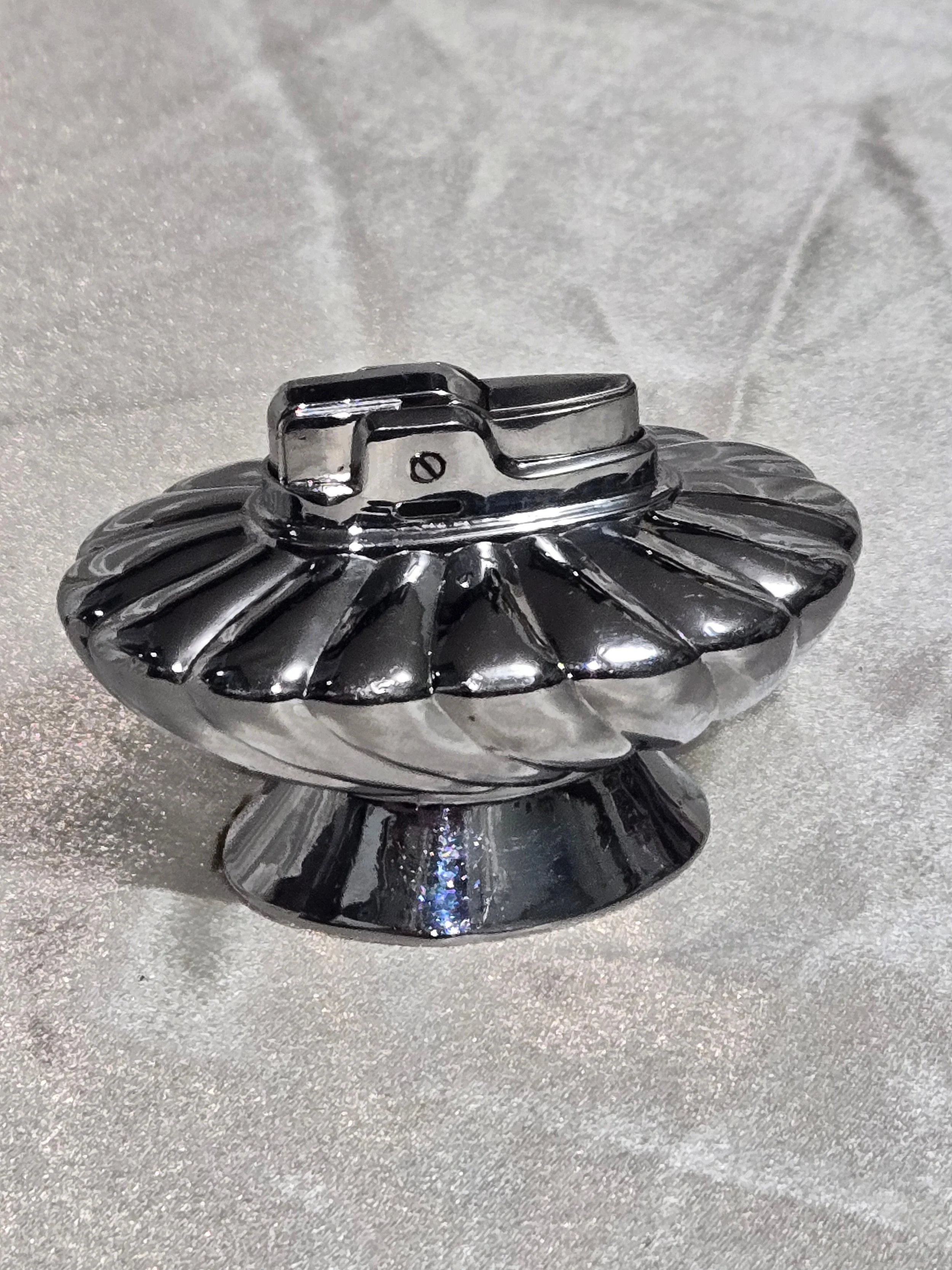 Vintage Ronson Regal chrome table lighter with swirl design, reflective silver finish, shown on silver backdrop.