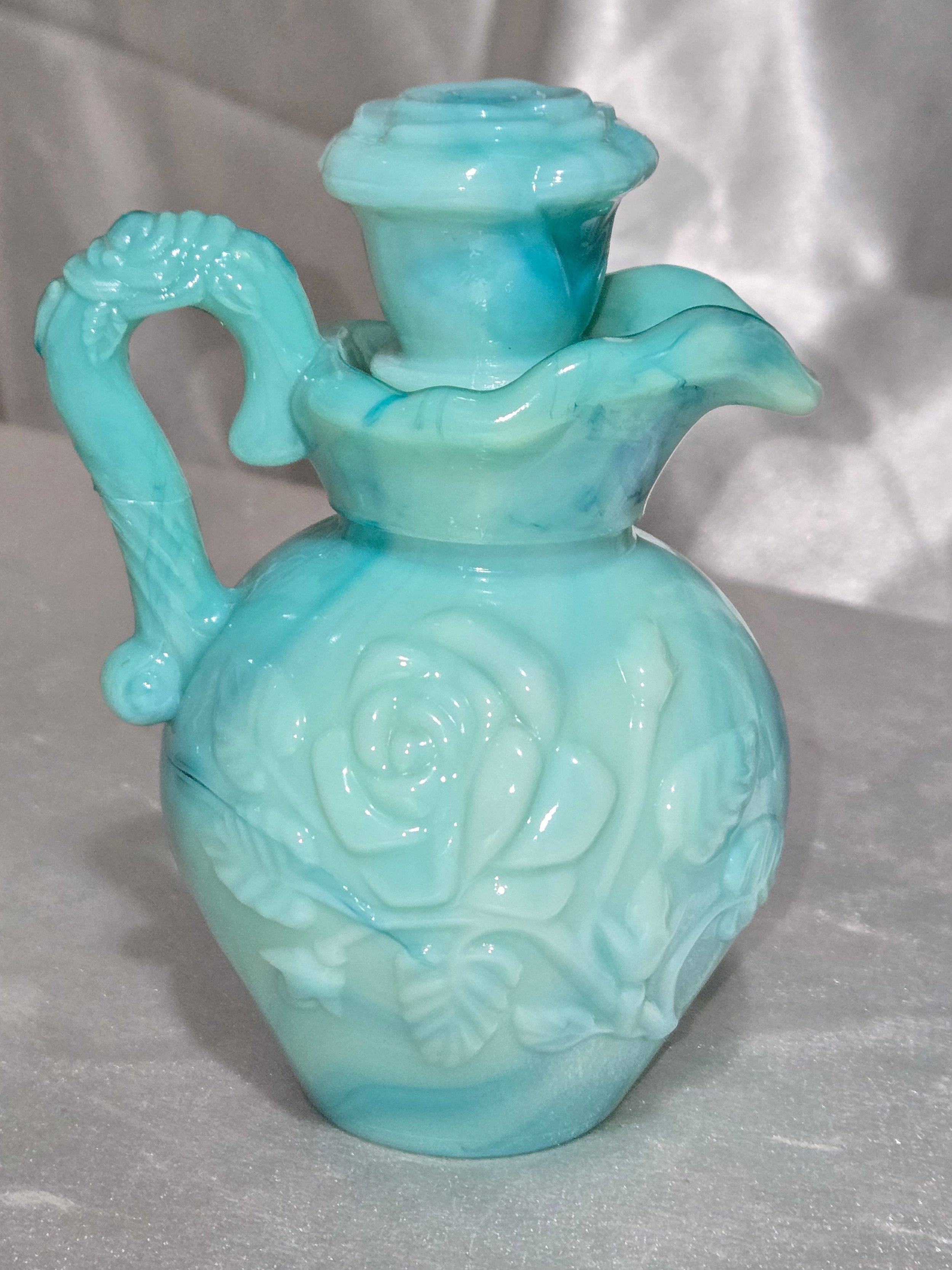 Close-up of vintage Avon jadeite look milk glass pitcher with raised floral pattern