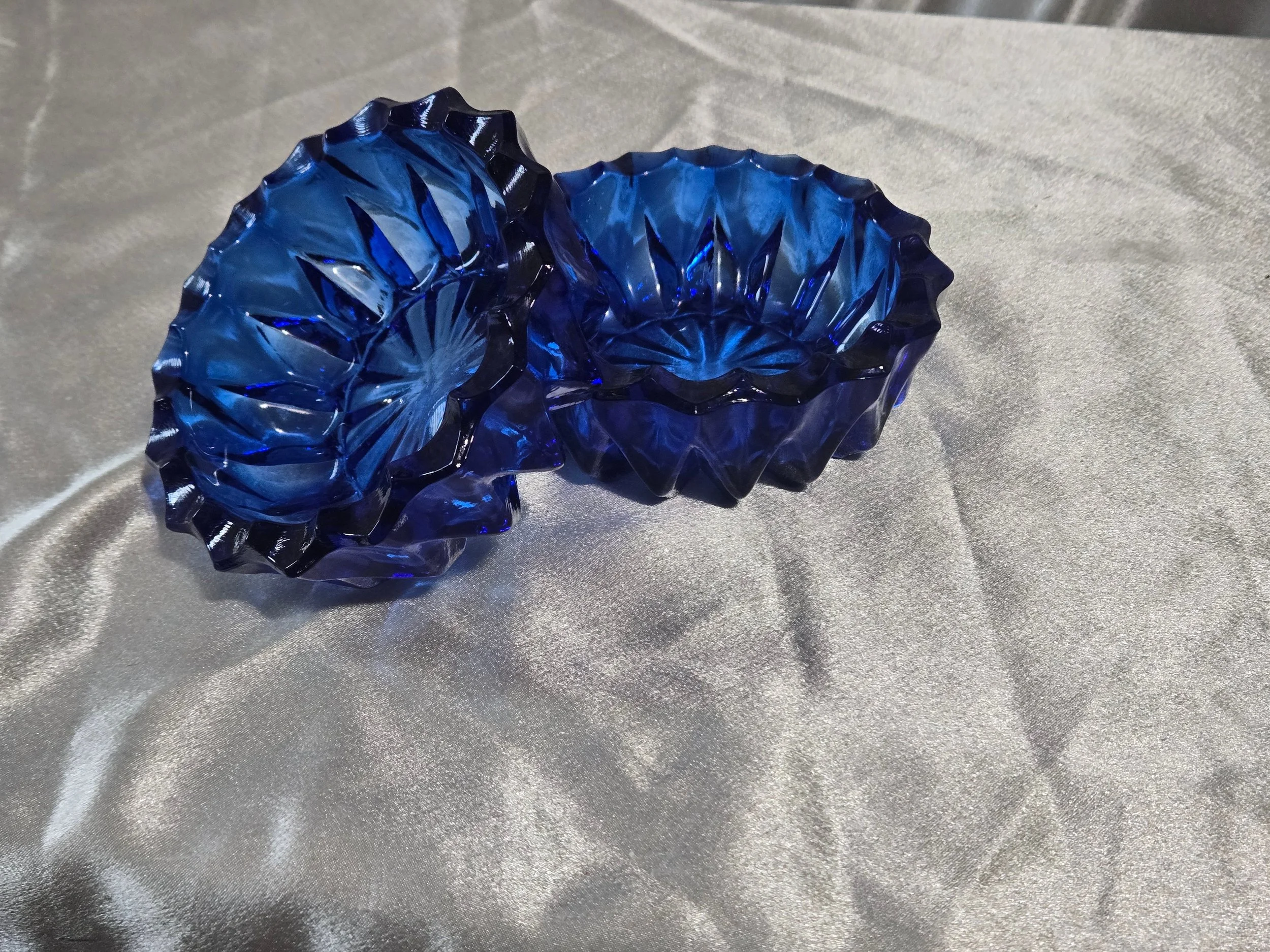 Pair of cobalt blue glass bowls with bowl sides up arranged with one bowl up and angled propped on other