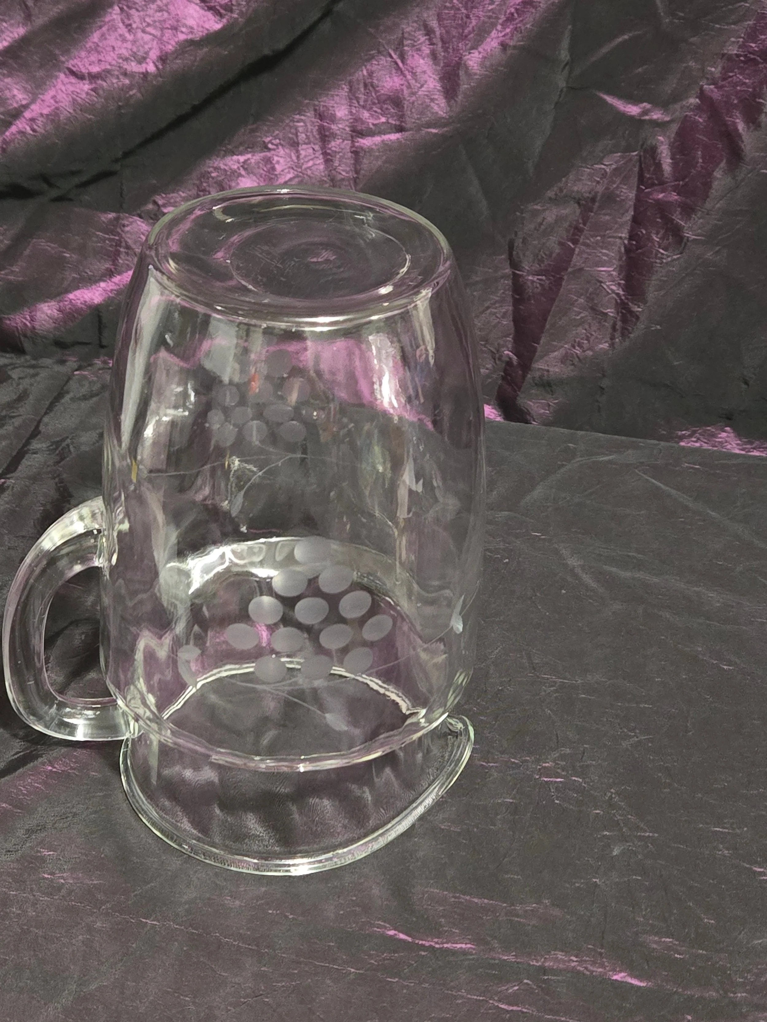 Clear glass pitcher etched with grapevine and crown designs, vintage mid-century style with curved handle and flared spout.