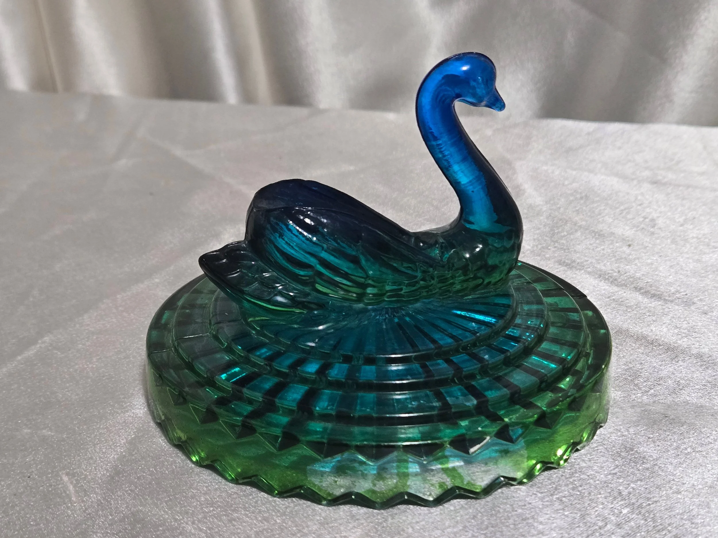 Side view of green glass swan candy dish showing textured pattern and sculpted bird lid