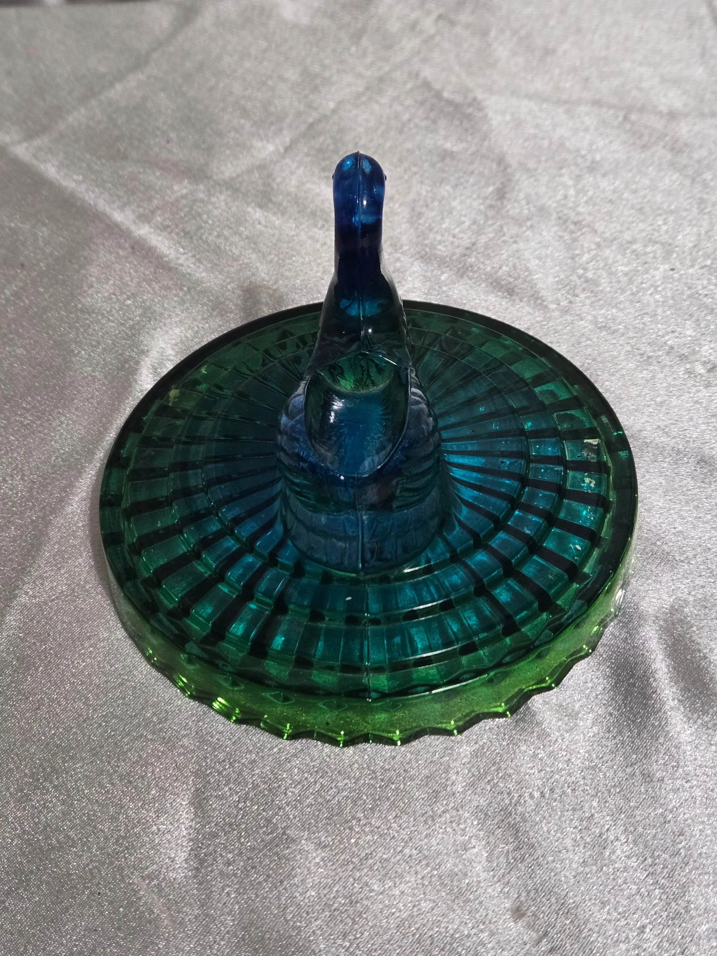 Front view of green pressed glass candy dish with swan lid and ribbed sides.