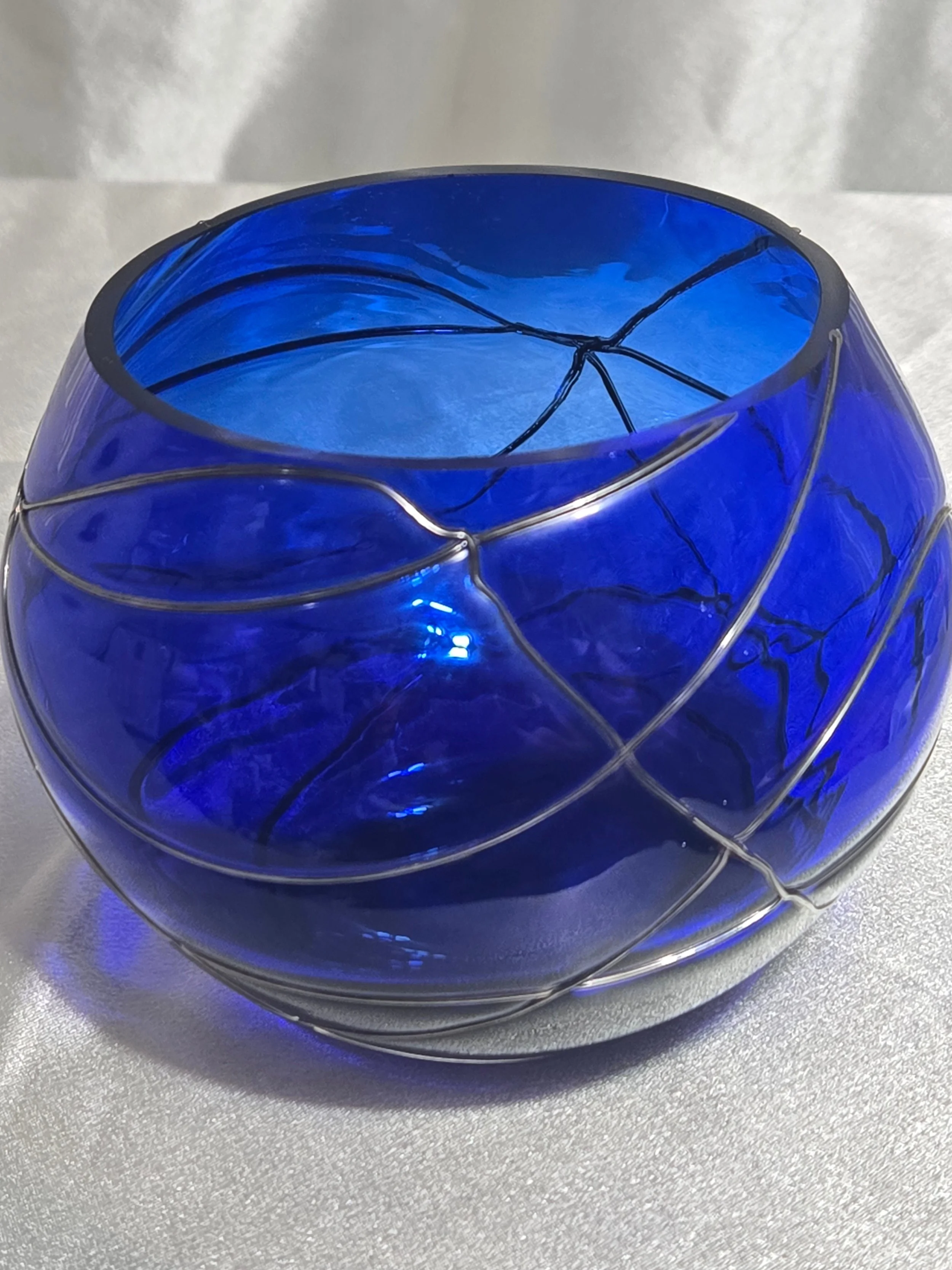 Cobalt blue hand-blown glass vase with silver swirl detailing, rounded art glass bowl, Murano-style decorative piece.