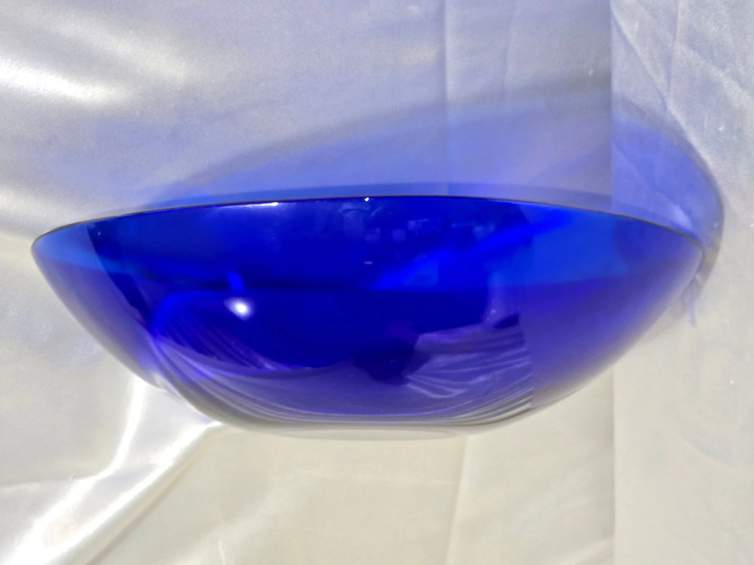 Large cobalt blue glass serving bowl displayed on neutral backdrop.