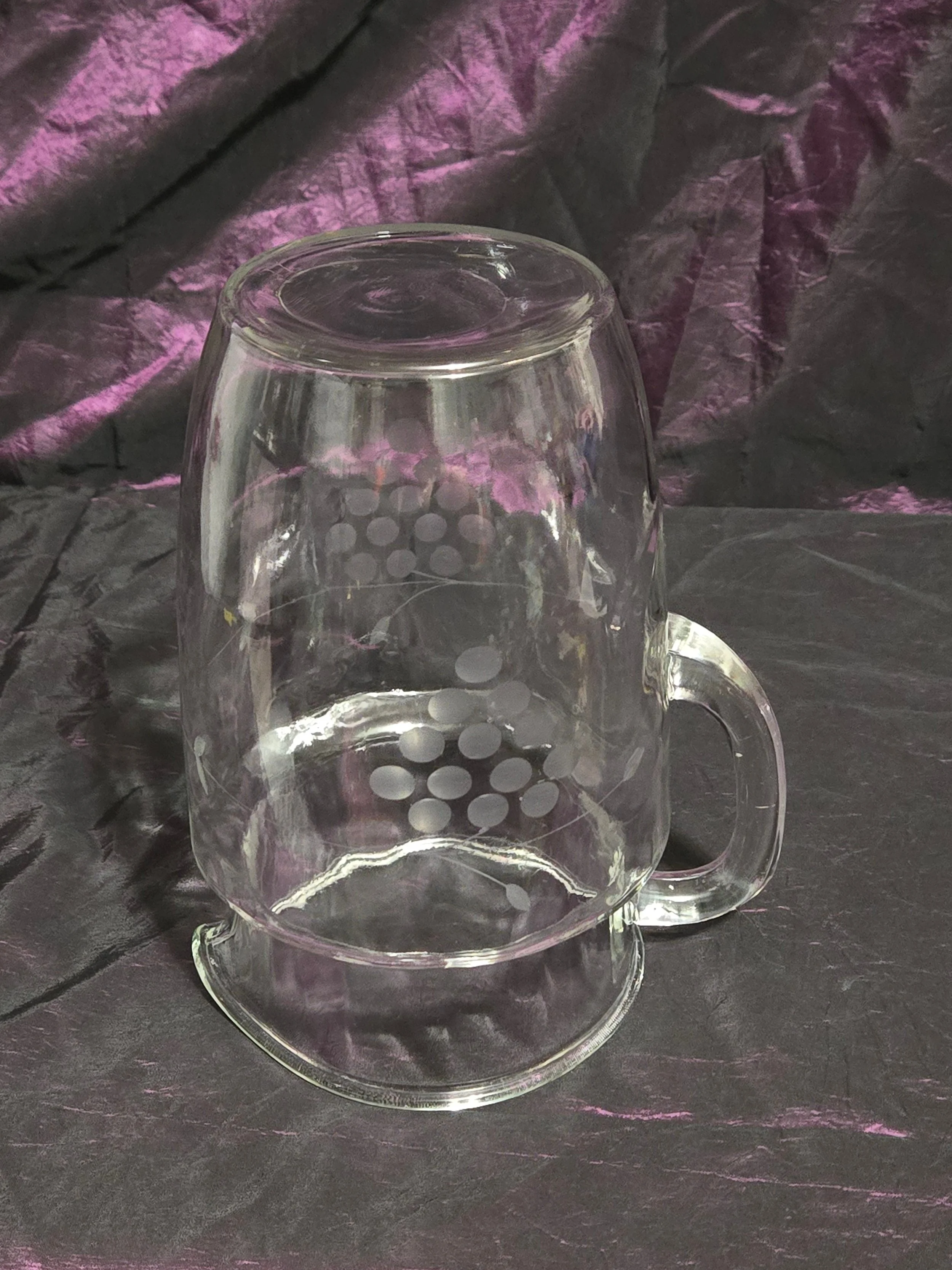 Clear glass pitcher etched with grapevine and crown designs, vintage mid-century style with curved handle and flared spout.