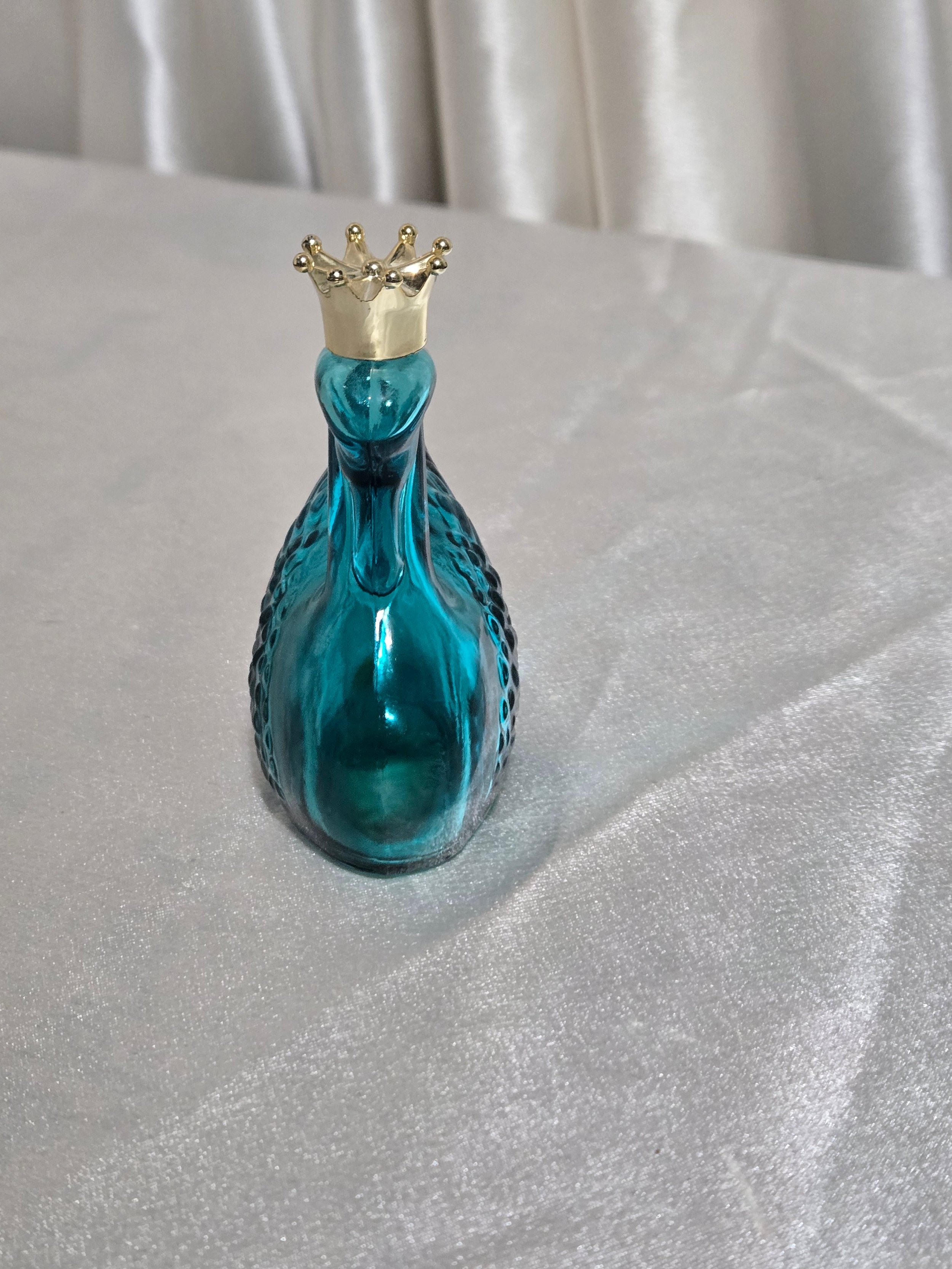 Front view of vintage Avon teal swan perfume bottle with gold tone crown stopper