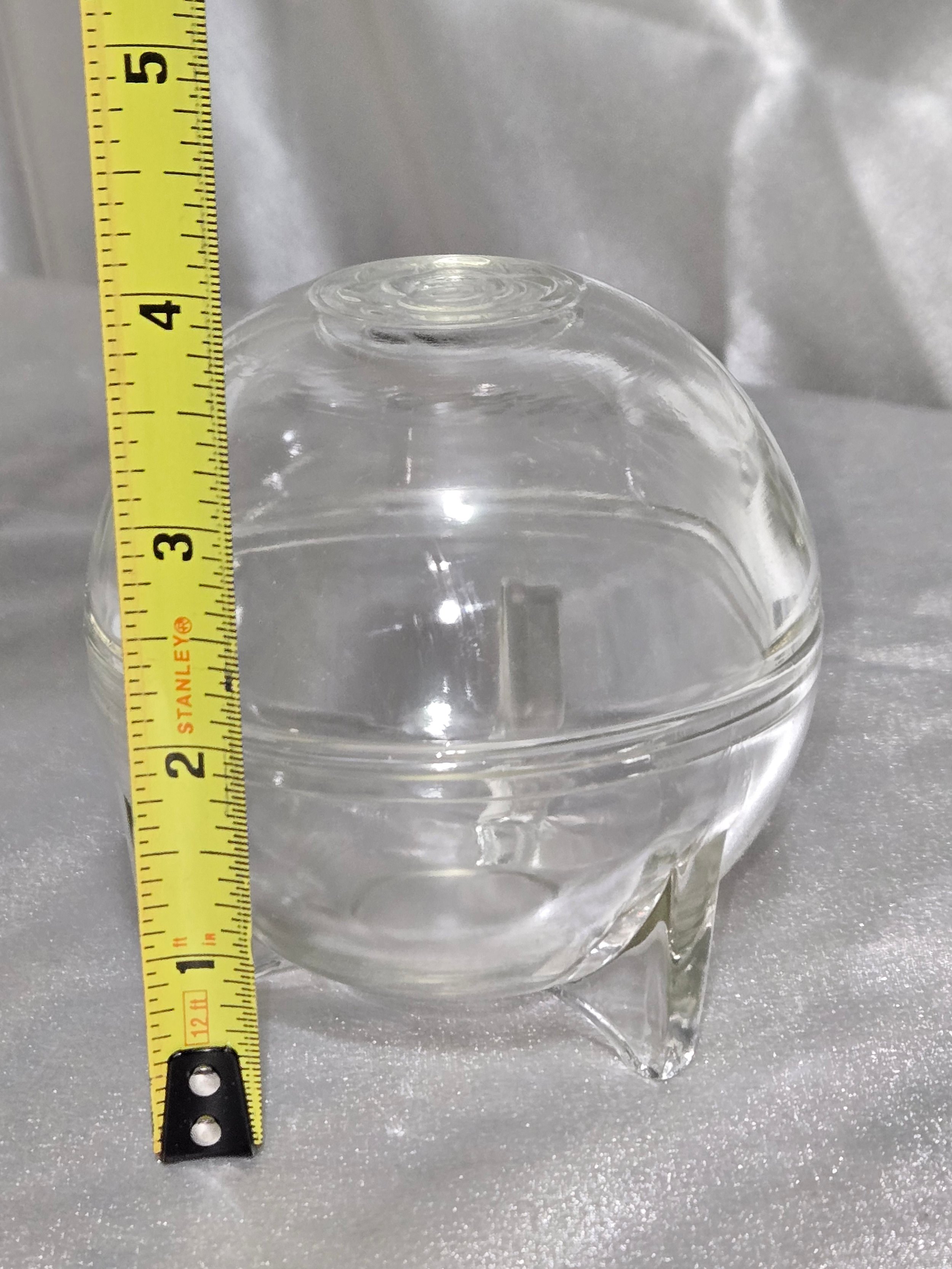 Vintage clear glass orb dish with rose embossed lid and three-footed base displayed on neutral background.