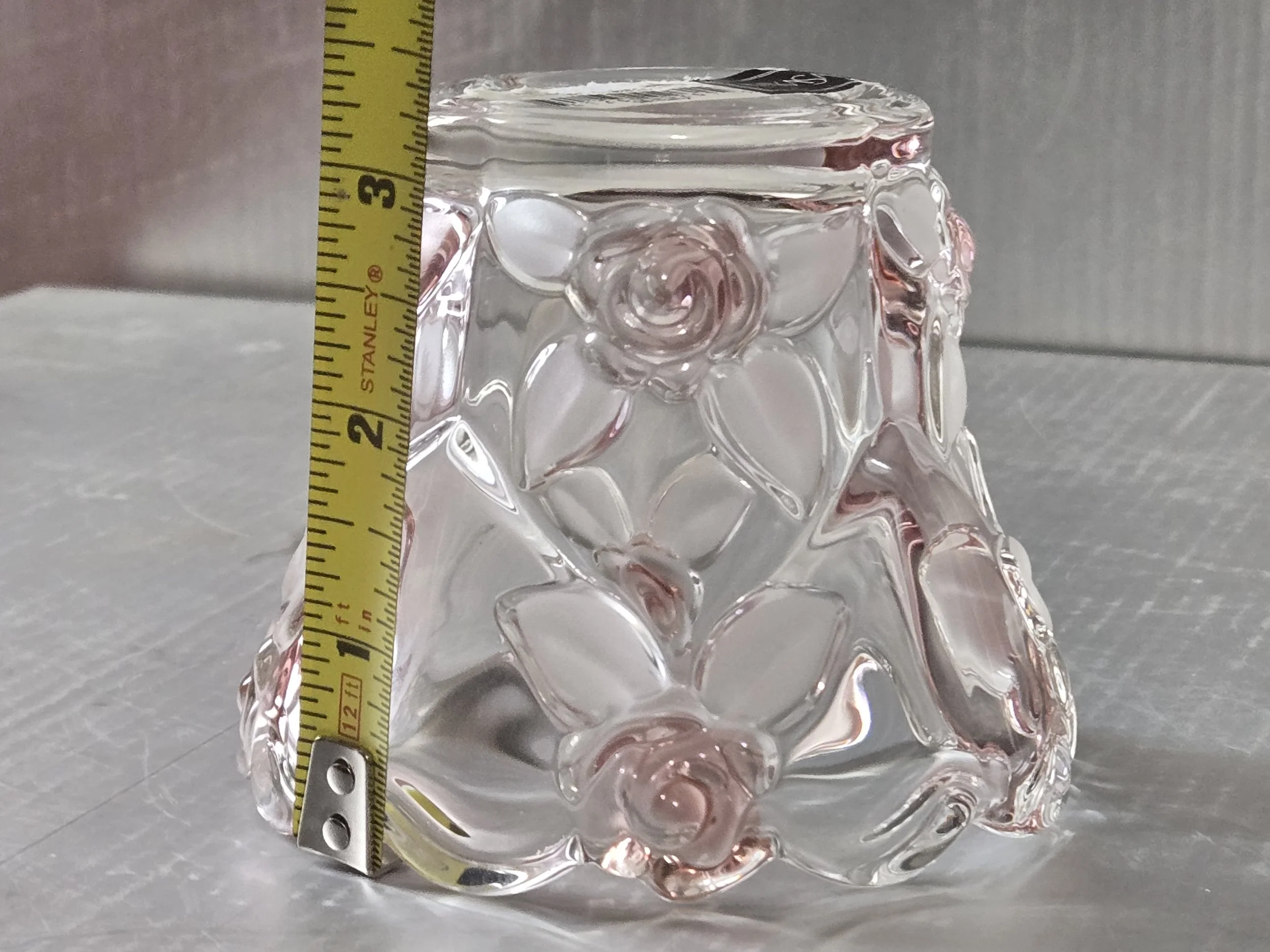 Pink glass votive holder with measurement tape showing height