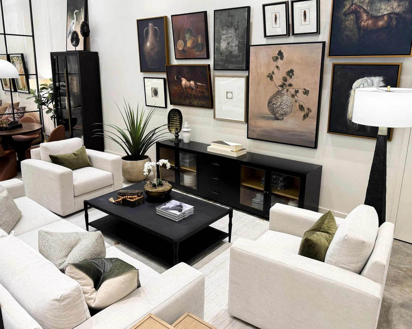 The gallery wall sets the tone.

A collected mix of artwork brings depth, contrast, and personality to this living room, turning the entire space into a moment. Paired with clean-lined upholstery, rich black accents, and touches of green, it feels cu