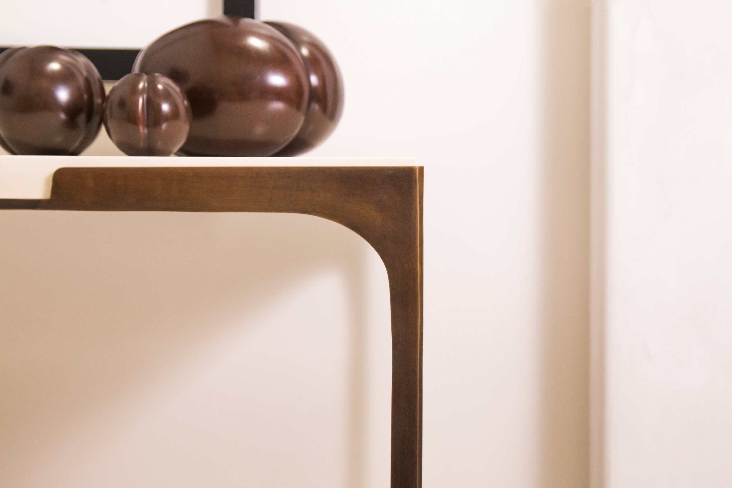 Close-up of a modern wooden table with decorative brown ceramic spheres on top, against a plain background.