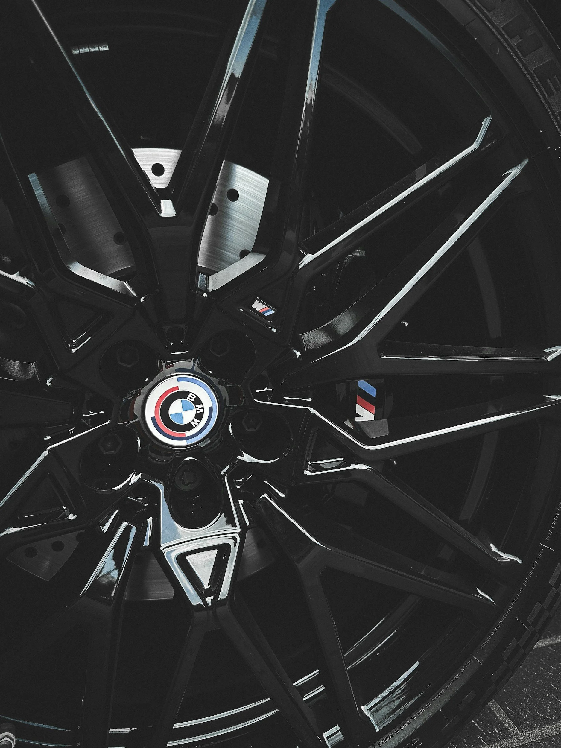 Een close-up van een BMW velg met het BMW logo in het midden, zwart en glanzend met metalen accenten.