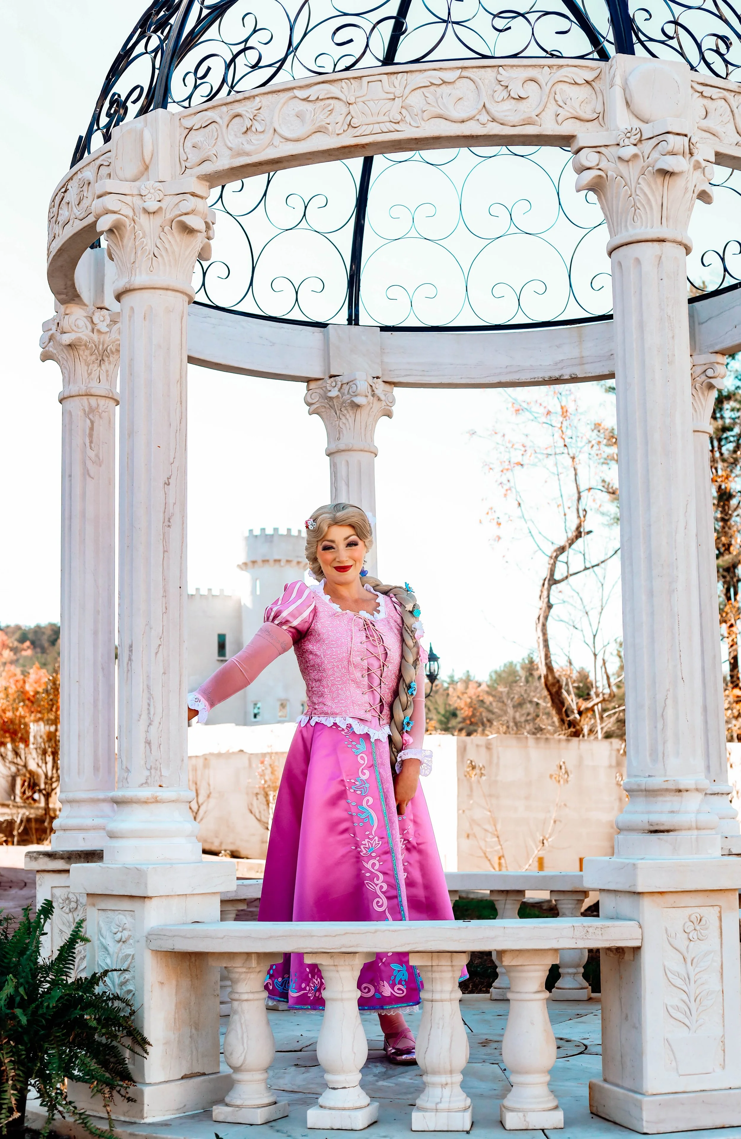 Woman dressed as a princess in a pink dress with a castle in the background.