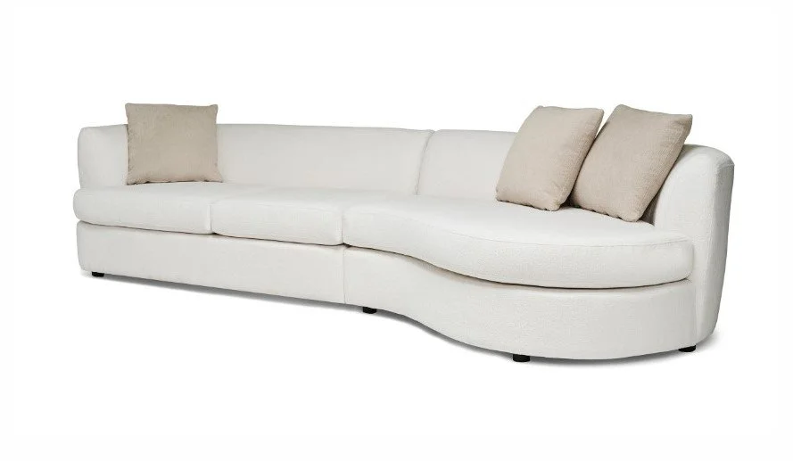 White sectional sofa with beige cushions in a living room.