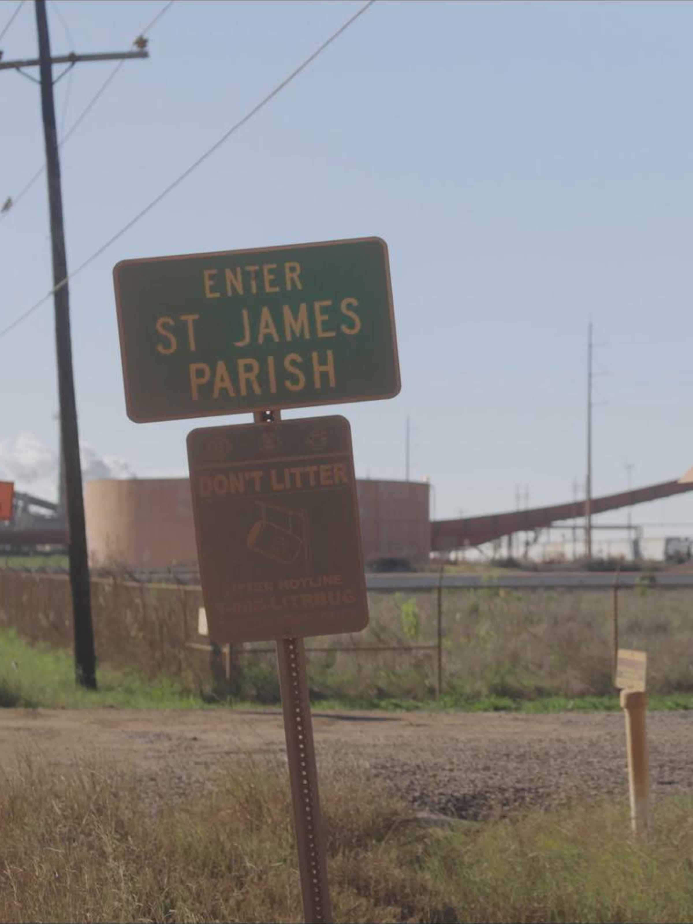 Roadside sign and utility pole against a clear blue sky with many power lines.