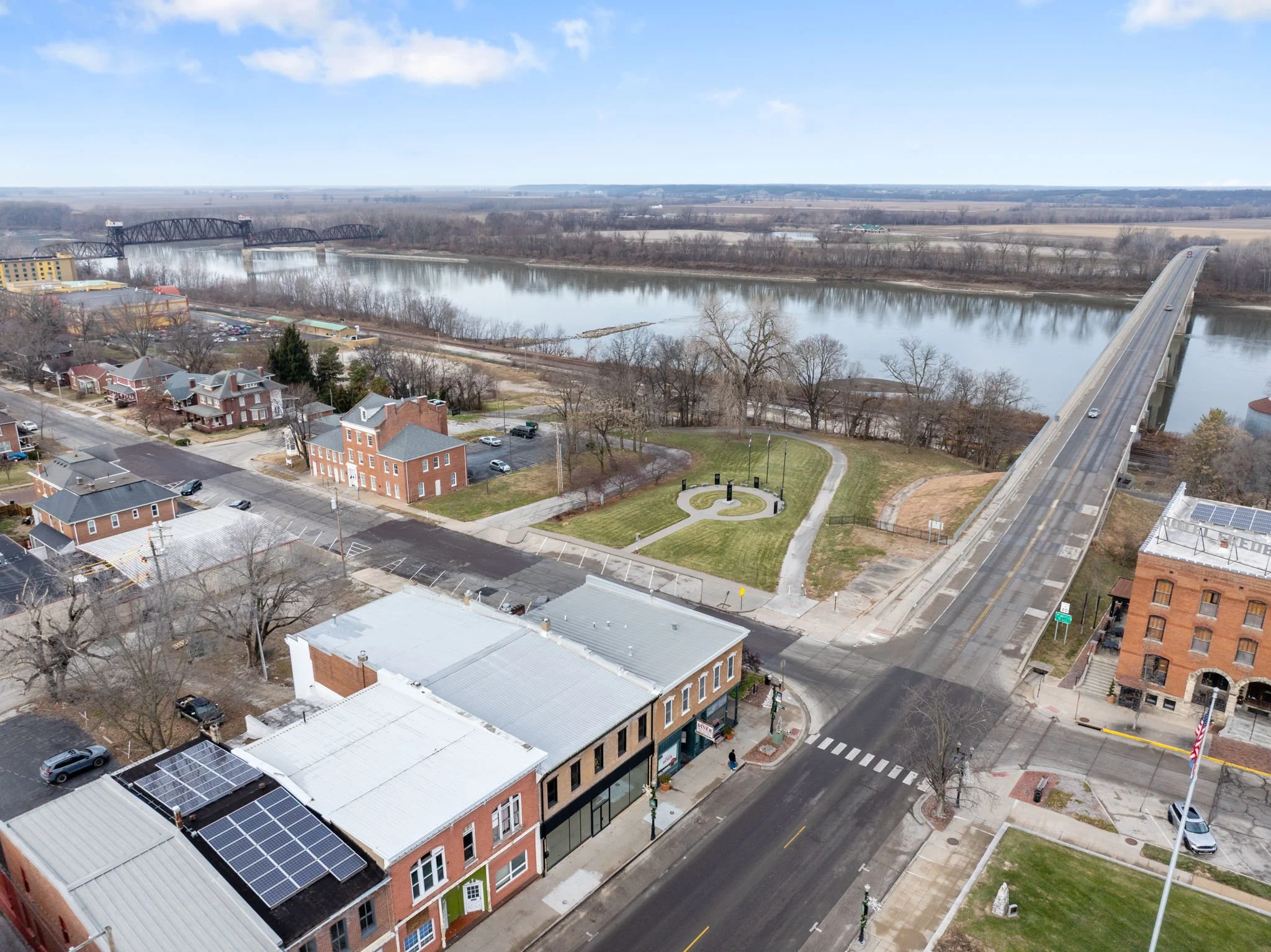 Aerial view of a small town with a river, a bridge and a park with a flagpole