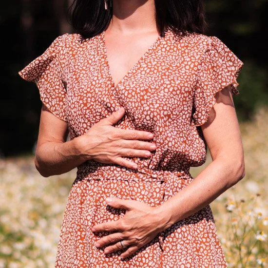 Frau im Sommerkleid meditiert auf Blumenwiese