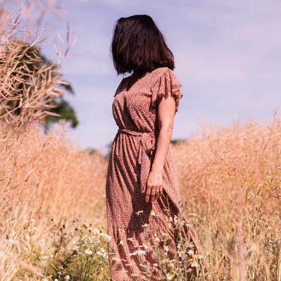 Frau im Sommerkleid tanzt im Blumenfeld