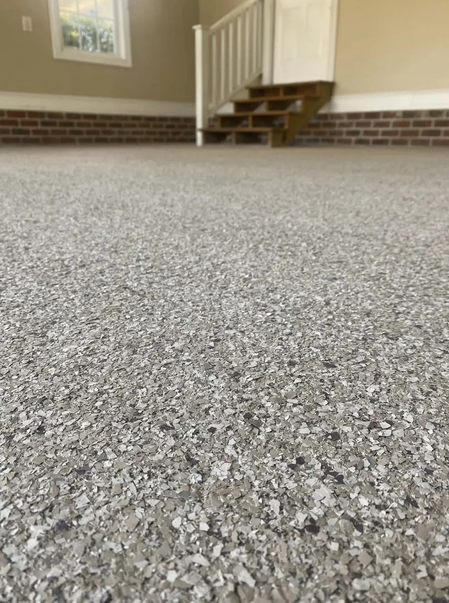 Close-up of a textured beige and gray carpet in a room with a staircase and a window in the background.