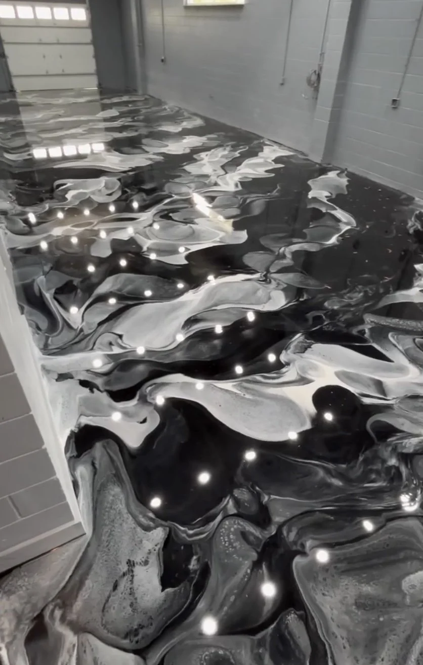 Garage floor with a black and white marbled epoxy coating with embedded LED lights.