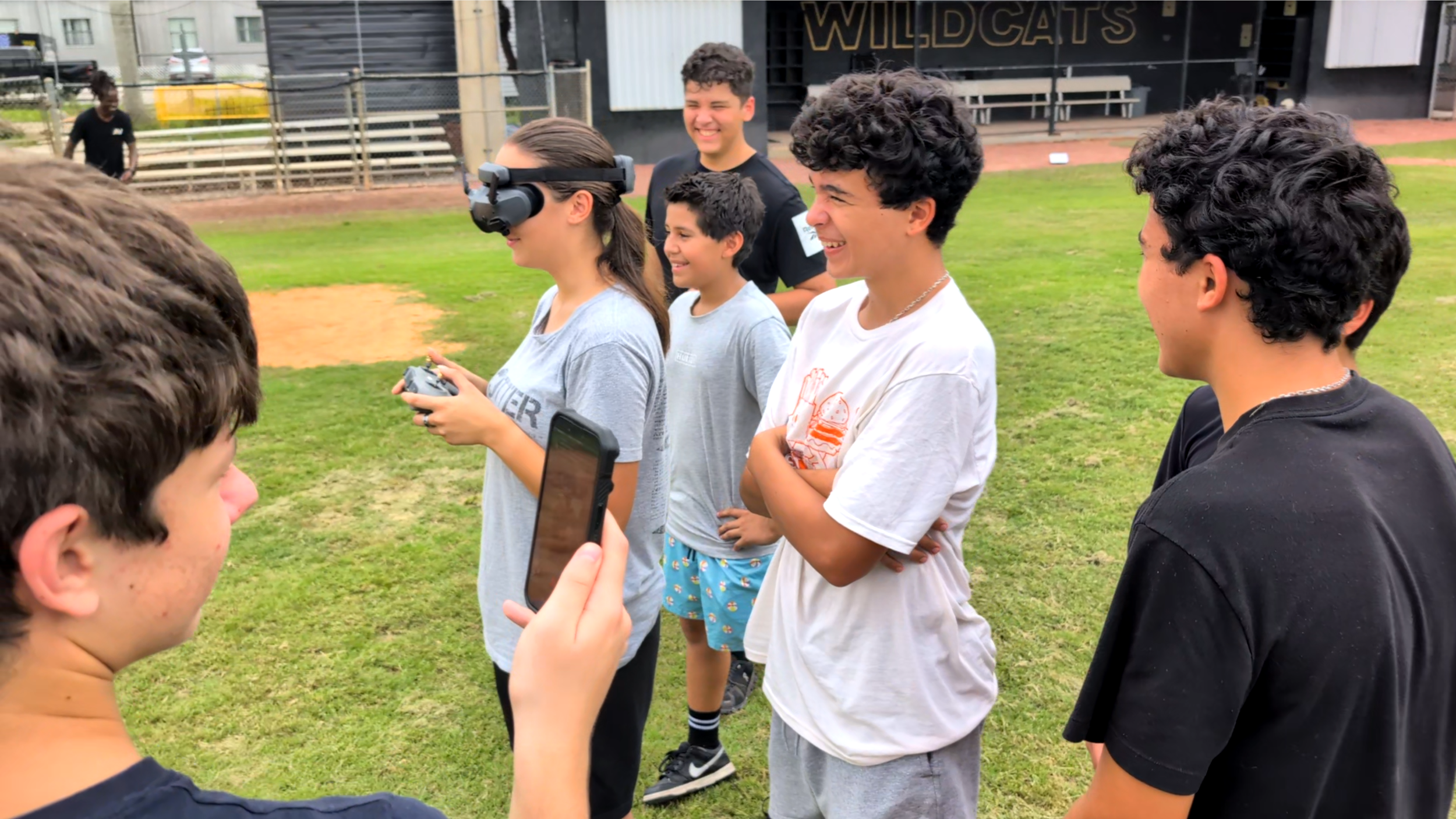 Western High JROTC cadet flying a drone with FPV goggles while teammates observe during outdoor field training