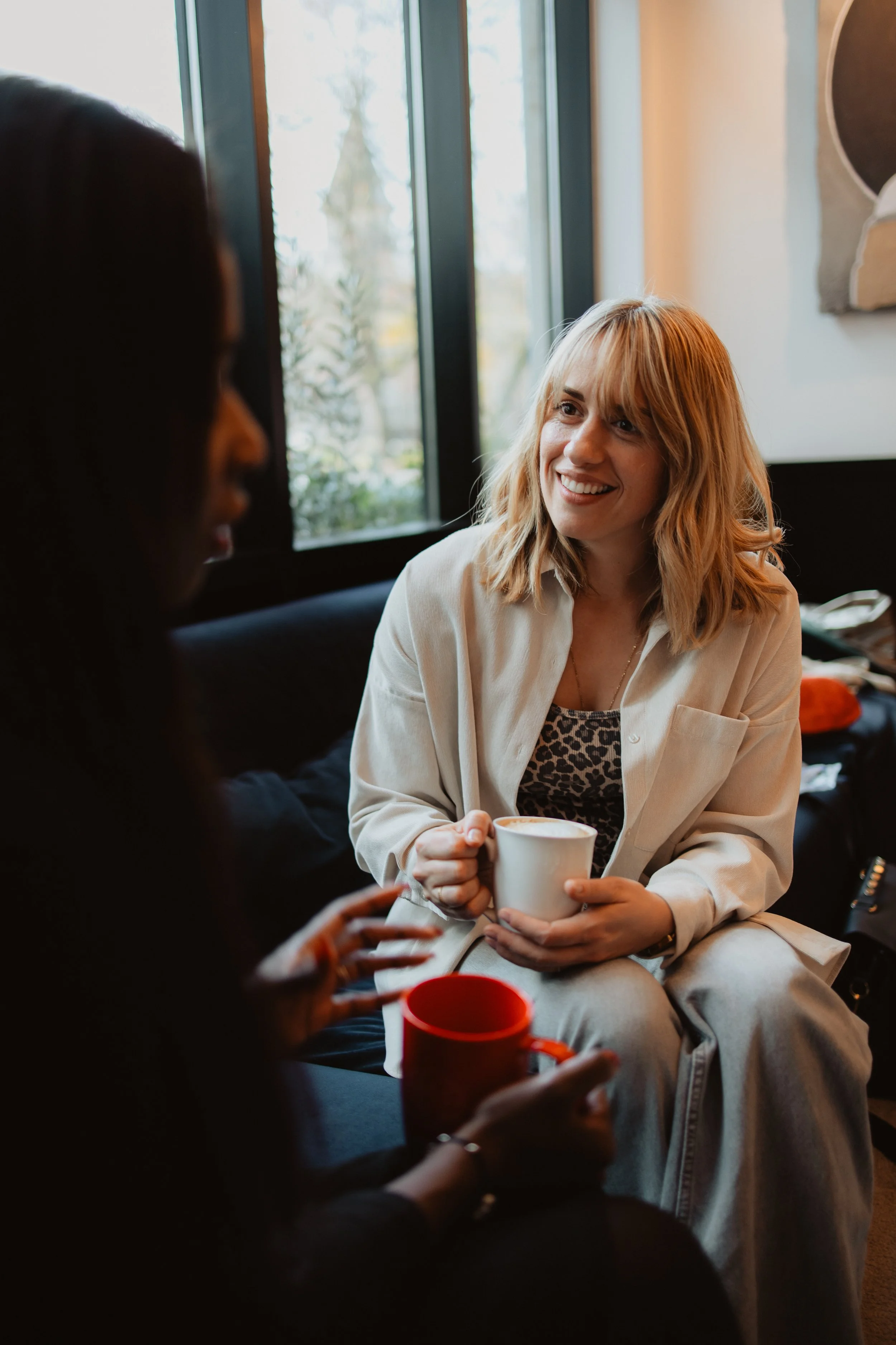 Deux femmes discutent dans un café, une d'elles sourit.