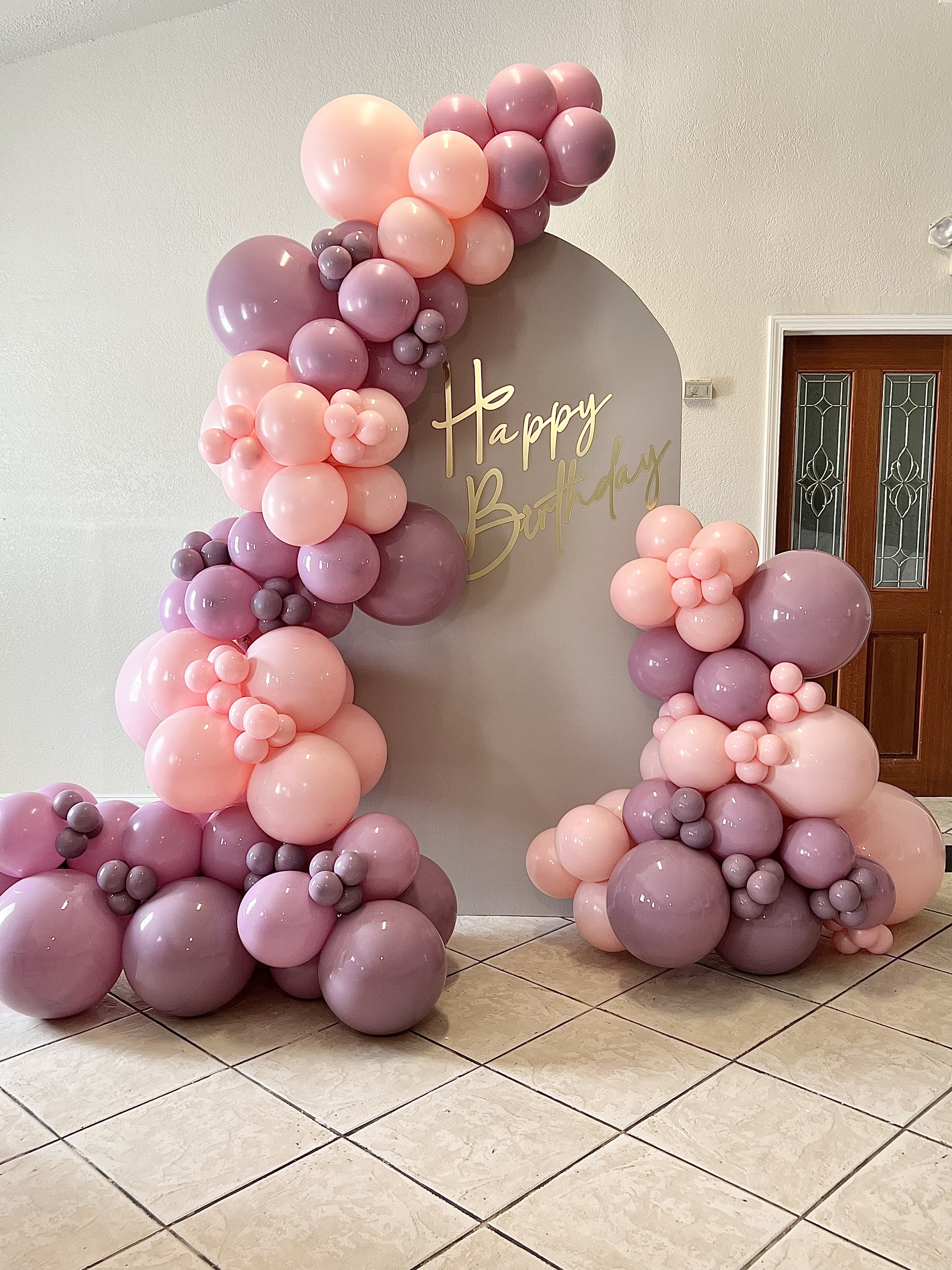 Pink, and mauve balloon garland on a chiara arch backdrop