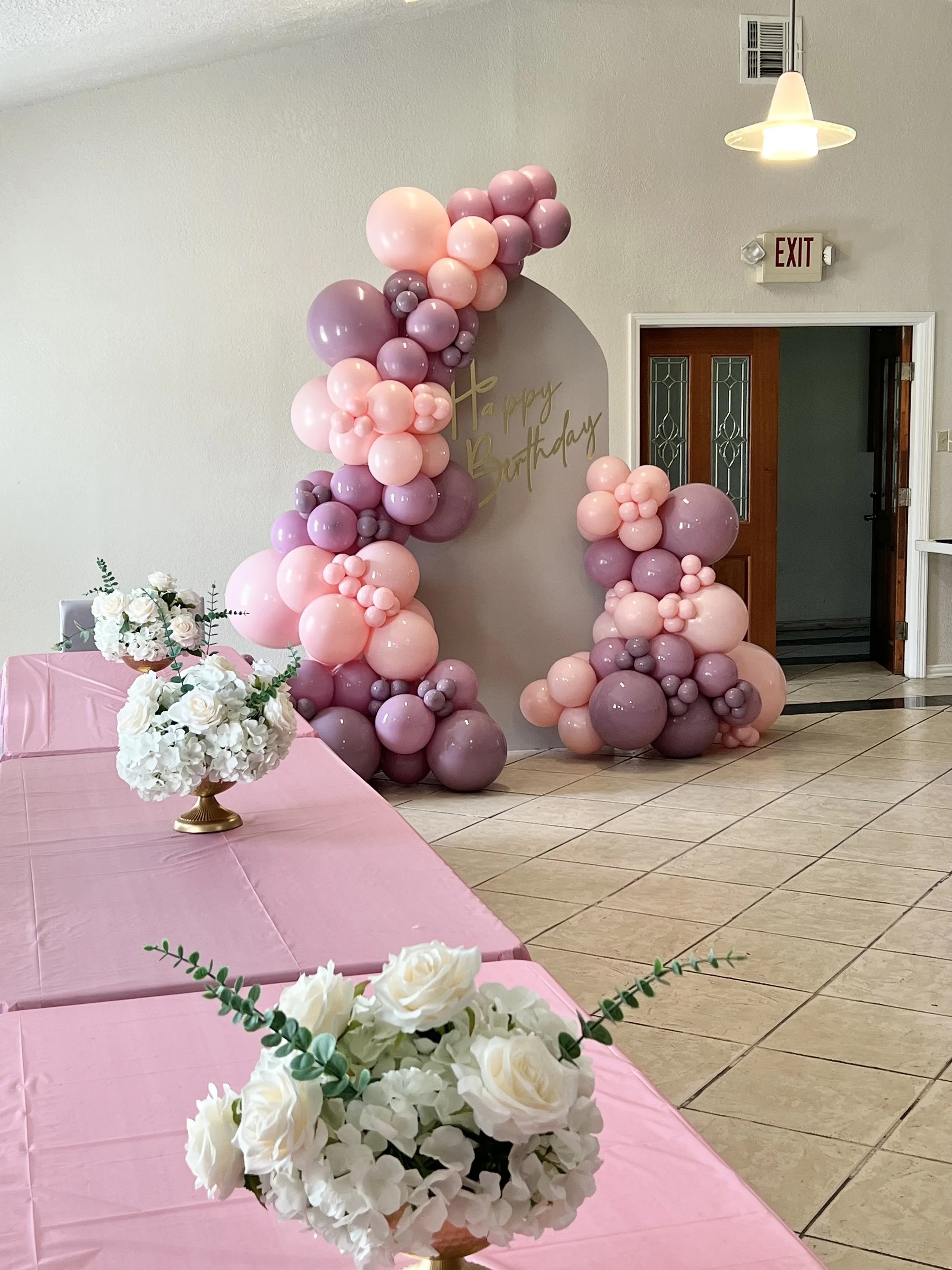 Pink, and mauve balloon garland on a chiara arch backdrop