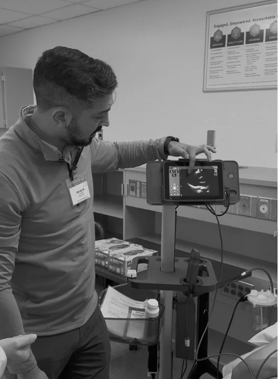 A man operating a portable ultrasound machine in a medical setting.