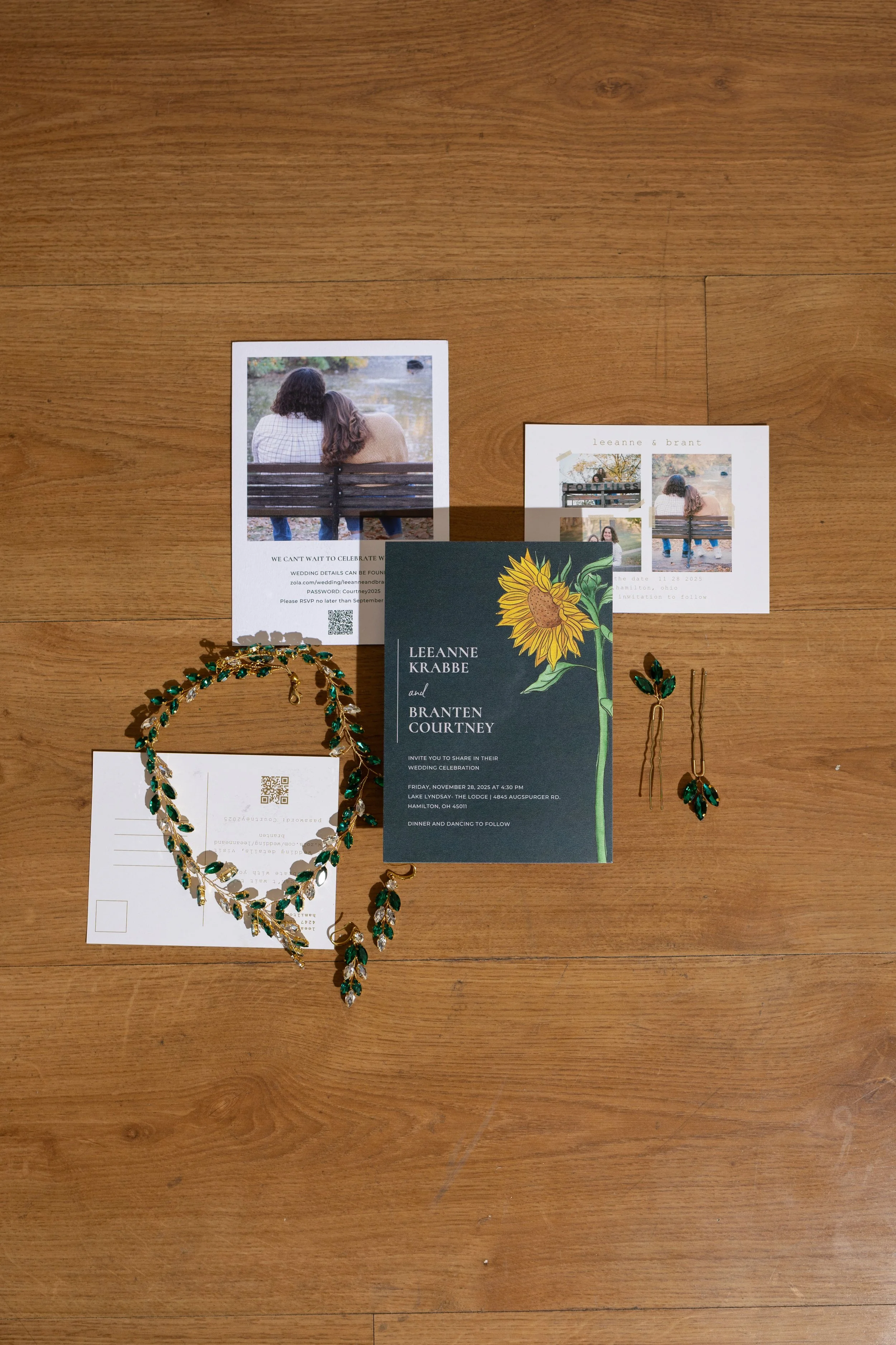 Wedding invitation suite with photos, jewelry, and accessories arranged on a wooden surface.