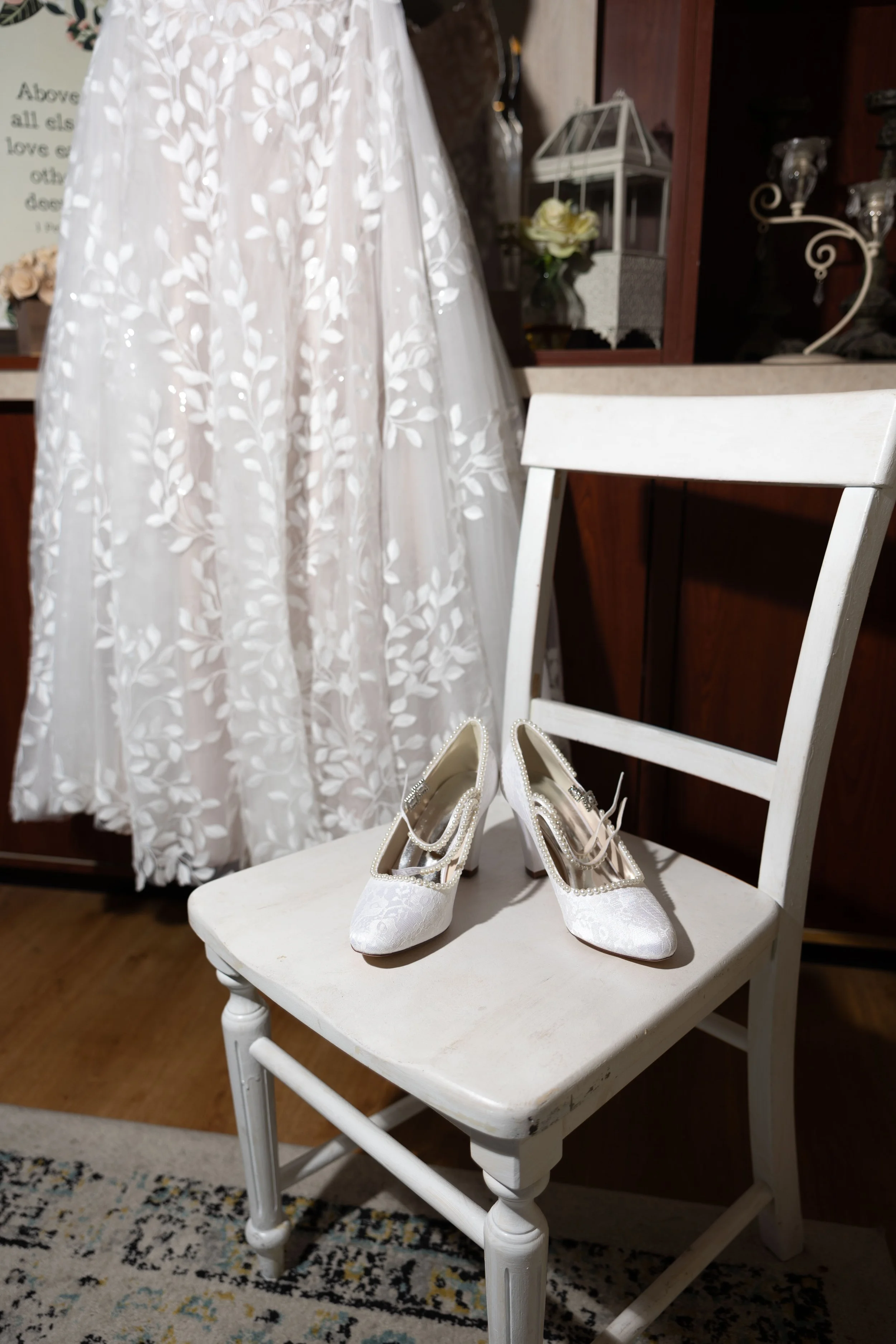 A pair of white wedding shoes placed on a white wooden chair.