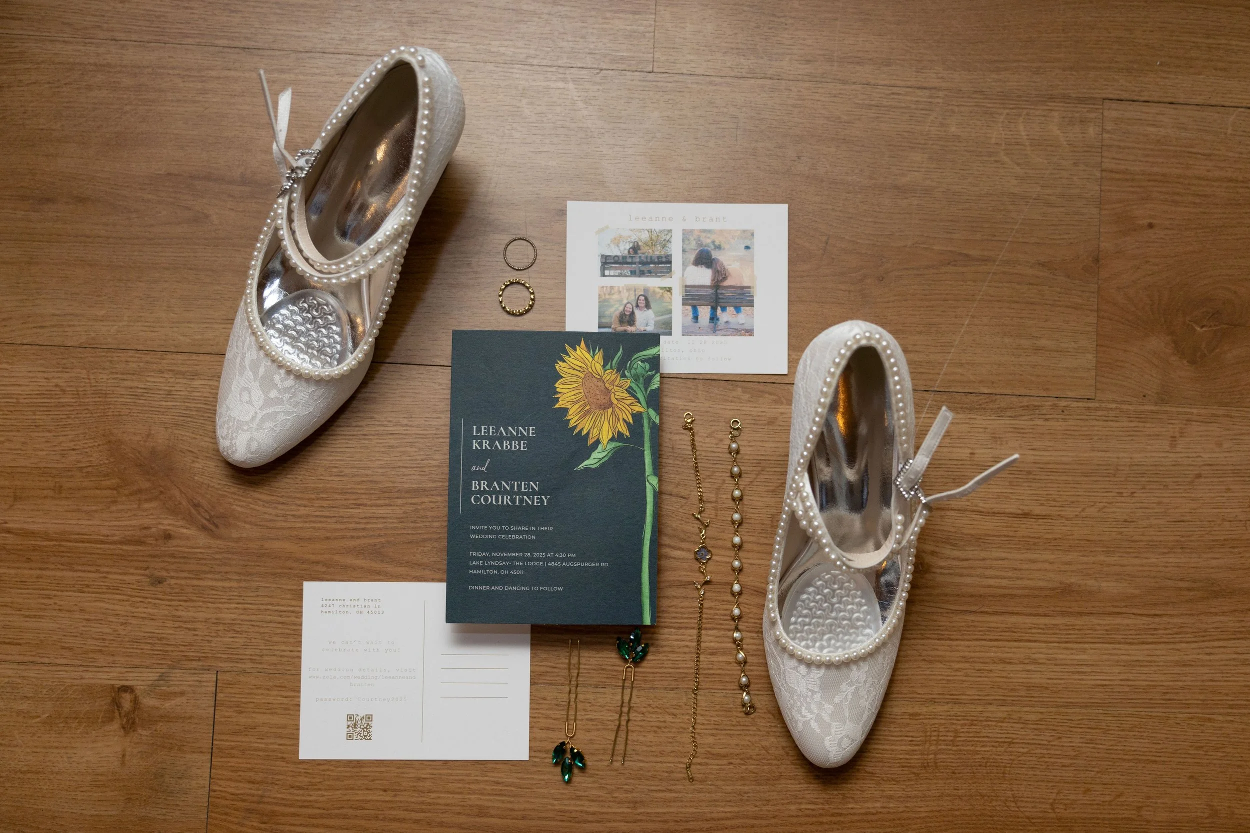 Wedding shoes, jewelry, invitation, and RSVP card laid out on a wooden floor.