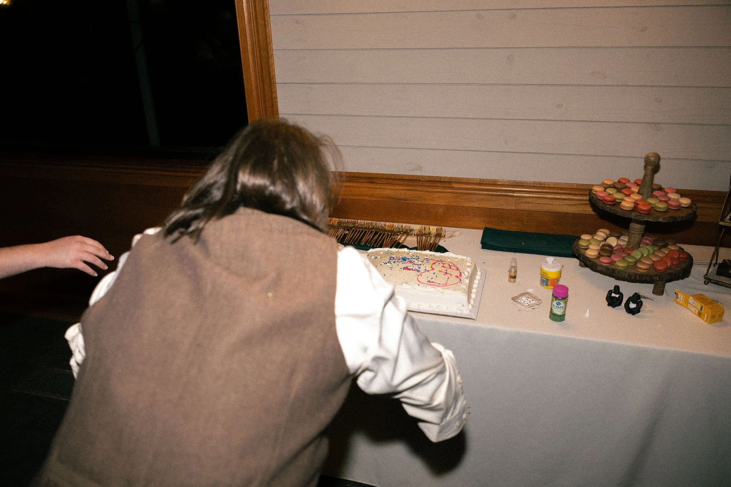 Person placing a candle on a decorated birthday cake at a celebration table.