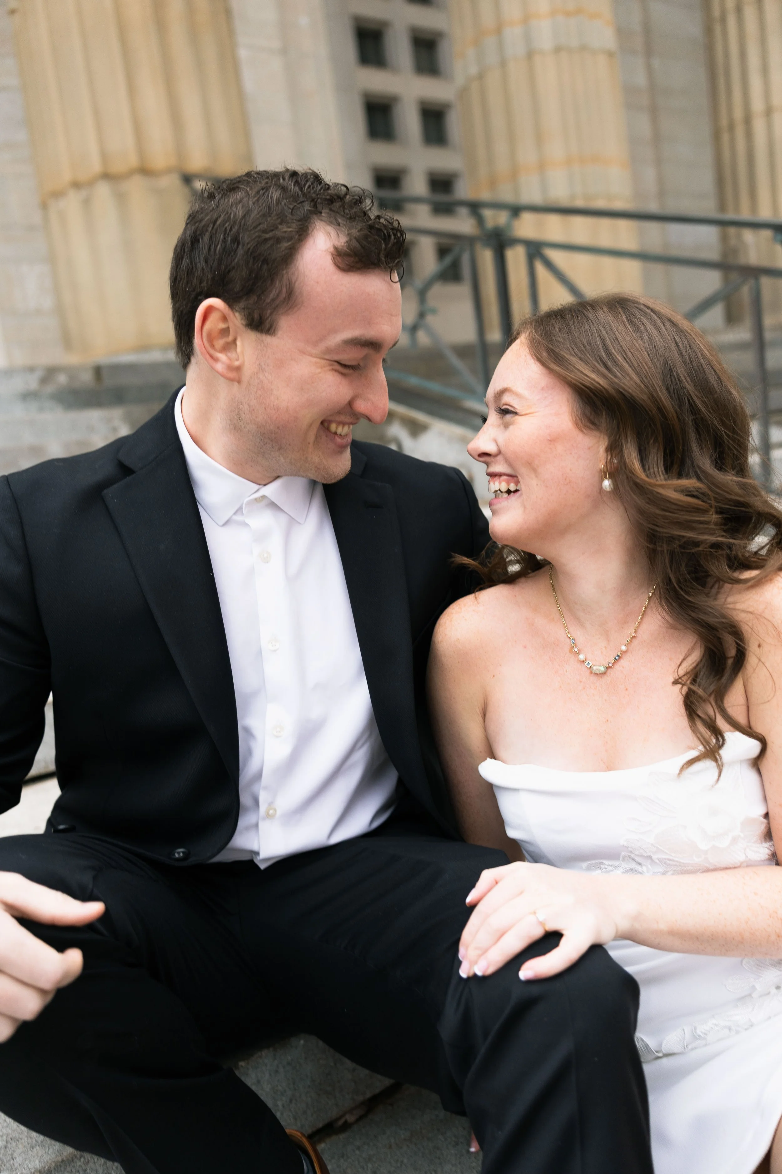 A couple in wedding attire smiling at each other
