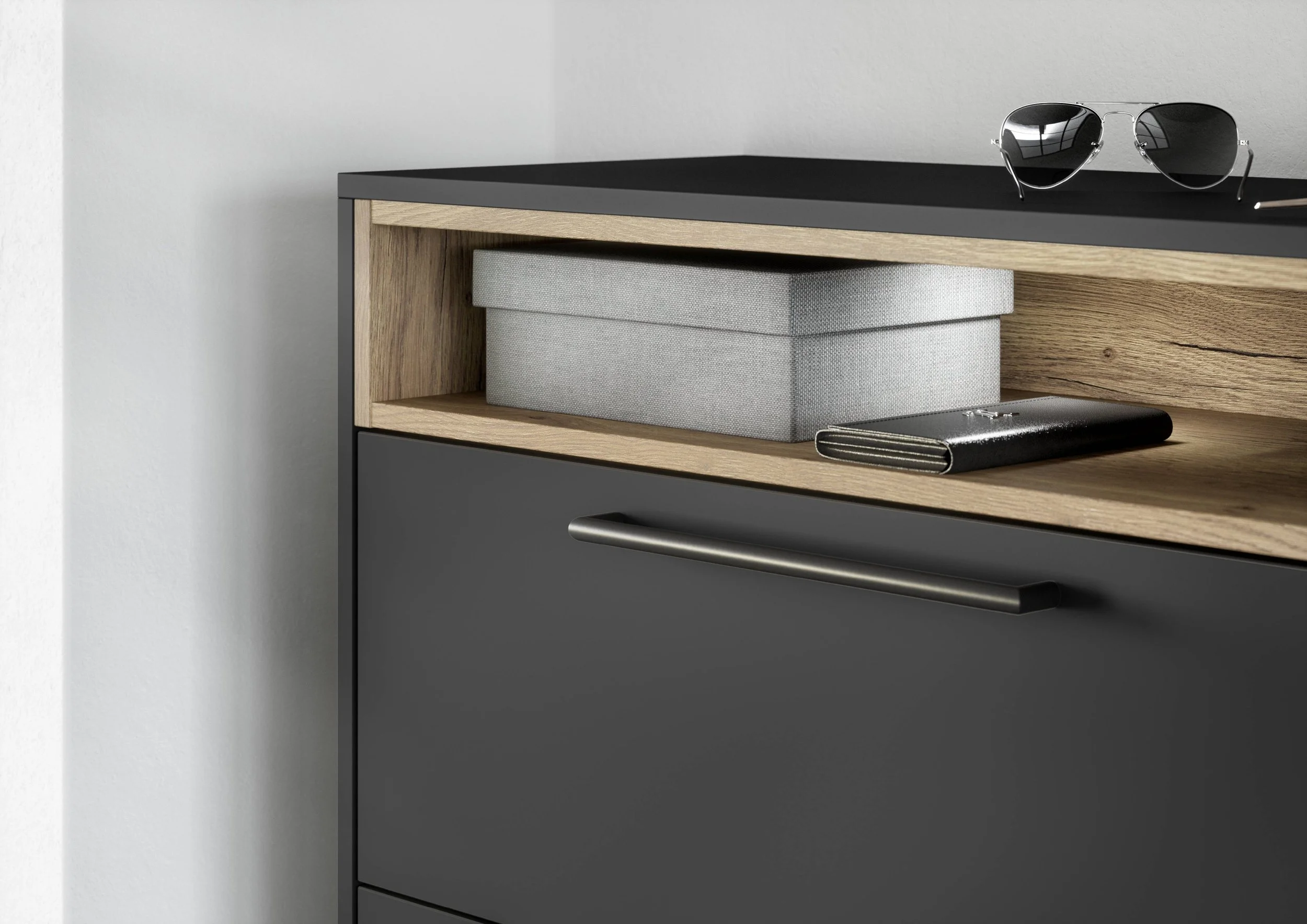 En mörkgrå skåp med ett trähylla som har en ljusgrå förvaringslåda och en bok eller plånbok. På ytan ovan skåpet ligger ett par solglasögon.