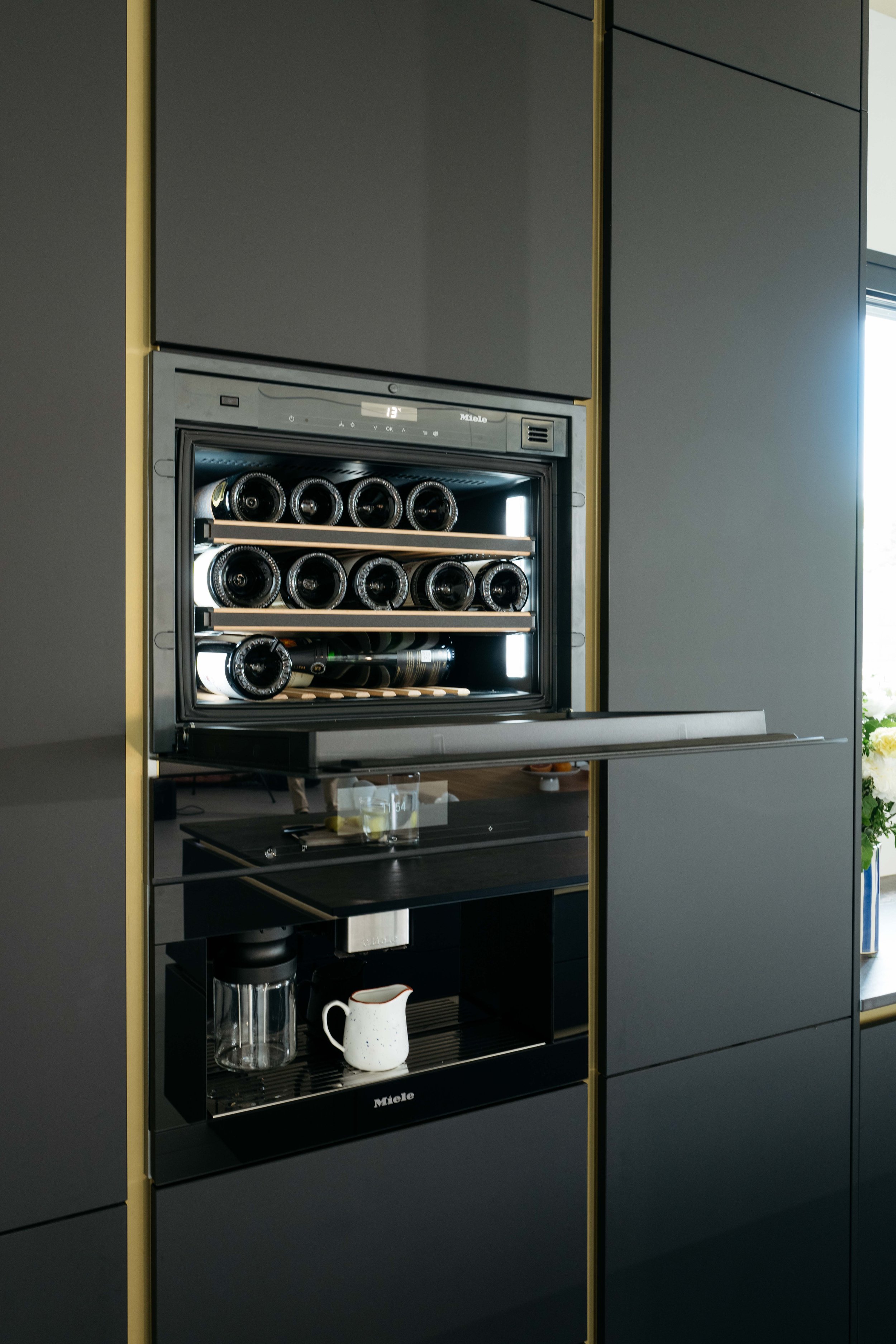 Vitt vin förvaras i en inbyggd vinkyl installerad i ett modernt kök med svarta skåpluckor.
