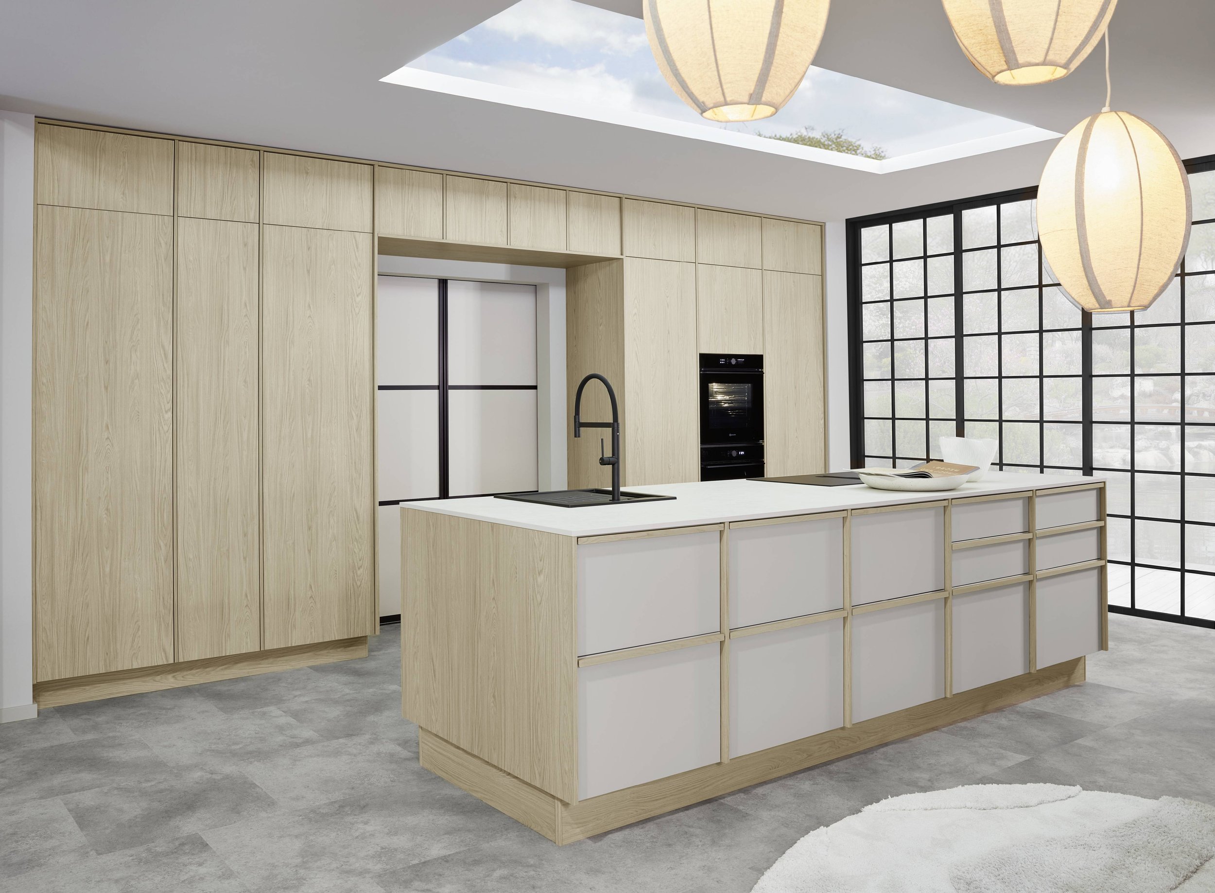 Modern köksdesign med ljusa träskåp och en köksö i vitt och trä samt stora fönster och hängande papperlampor.