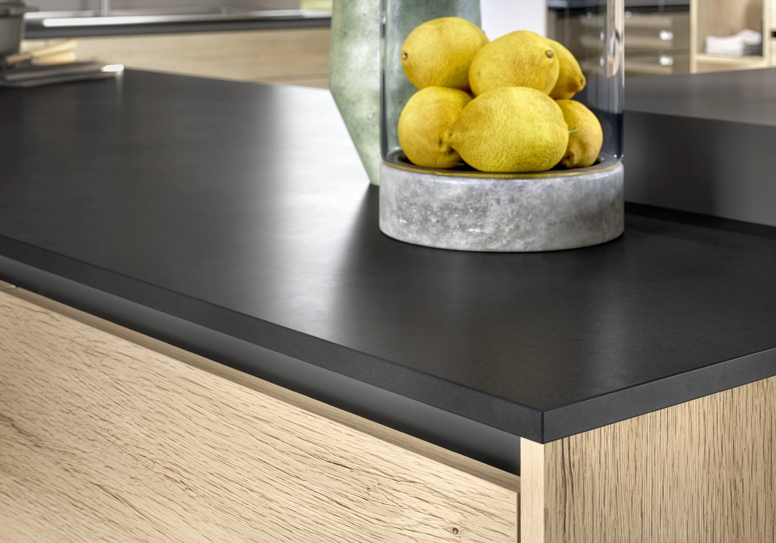 Dekoration med gula citroner i en glasburk på ett svart och träfärgat bord.