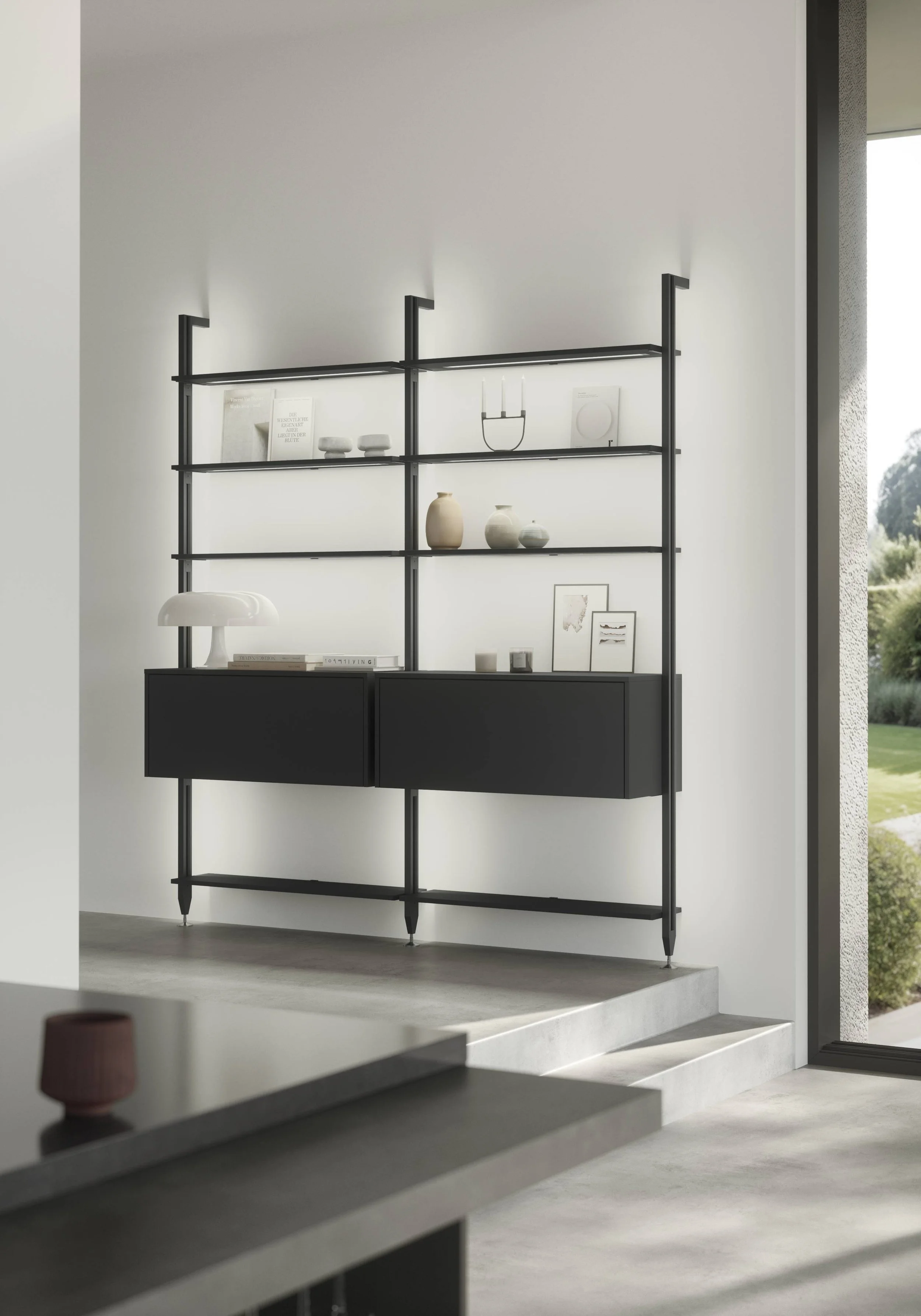 En svart bokhylla med tre hyllor och två luckor, dekorerad med vaser, böcker och konst på en vit vägg i ett modernt rum.