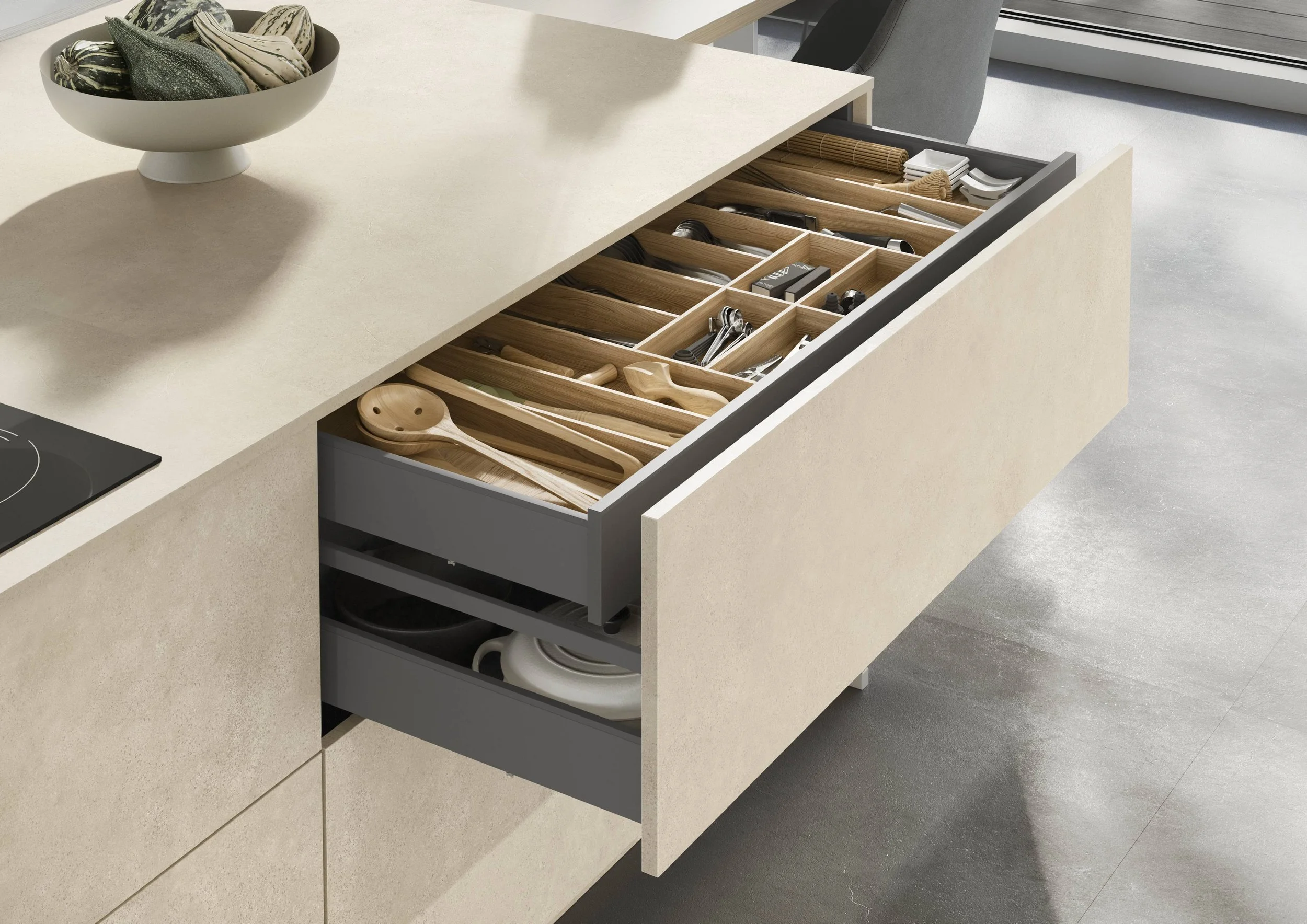 En kökslåda fylld med trämaterial och köksredskap, inklusive skedar, knivar och annat köksutrustning.