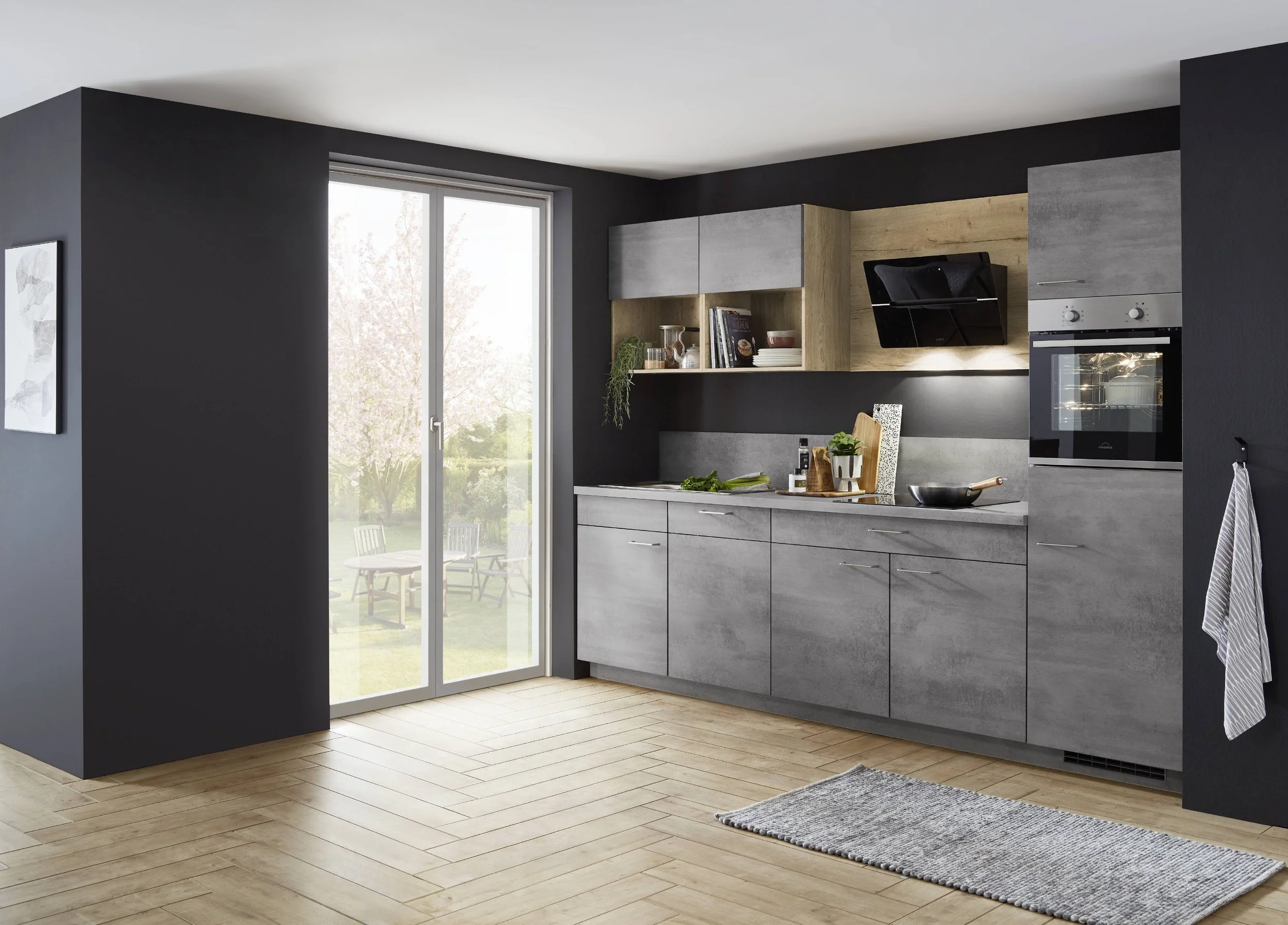 Modern kök med svarta väggar, läderskåp i grått och trädetaljer, stor fönster som vetter mot en trädgård med utemöbler, trägolv och en matta på golvet.