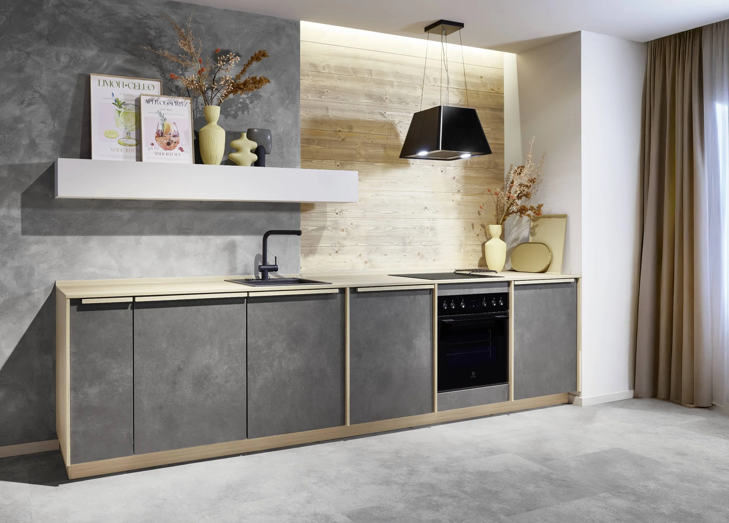 Köksinteriör med minimalistisk design, mörka skåp, grått och trämönstrat väggmaterial, och dekorativa vaser på hyllor och bänk.