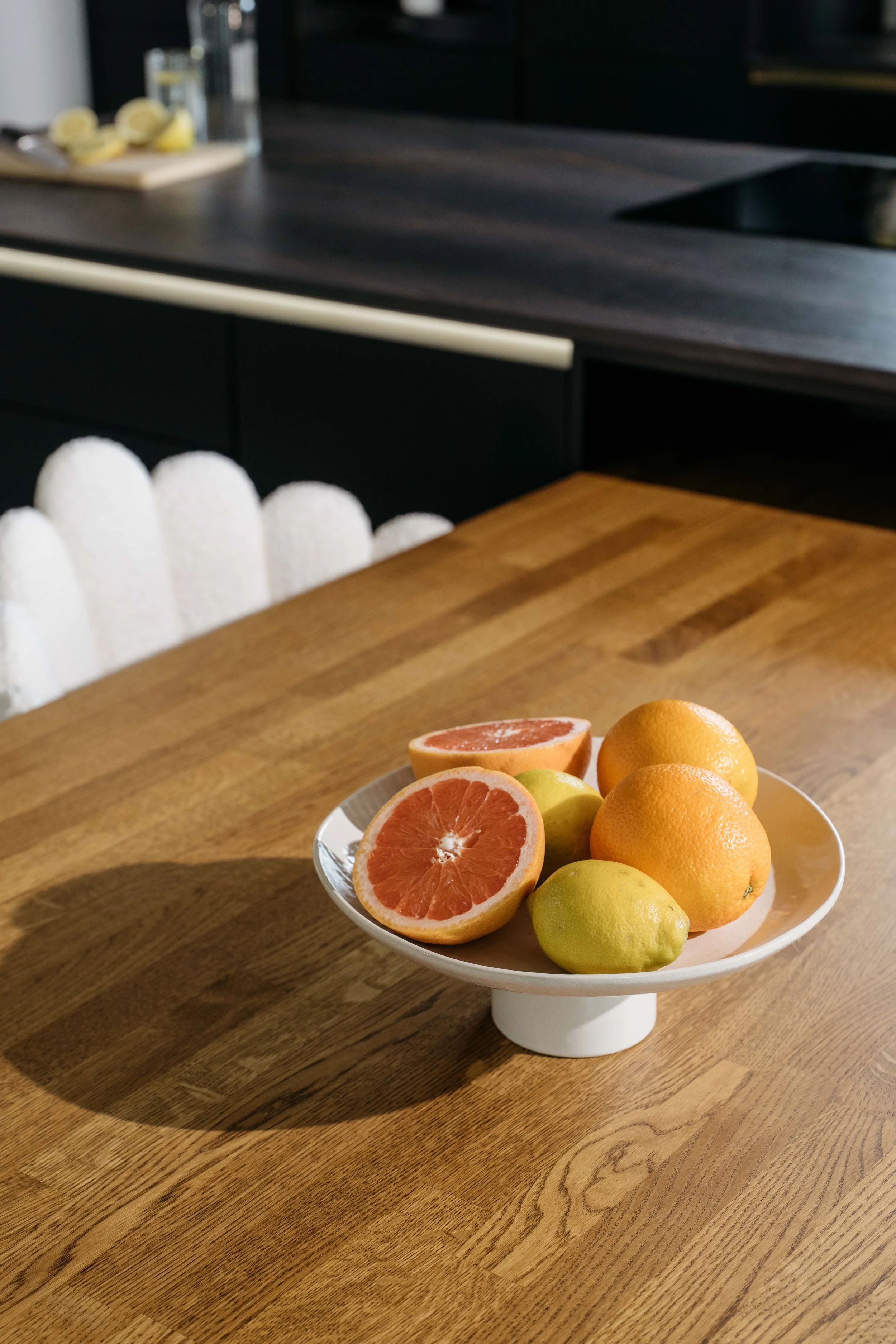 Skål med grapefrukt, citron och mandarin på ett träbord i ett kök.